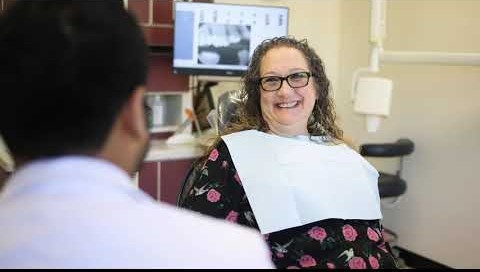 A dentist talks with a smiling patient during a dental check-up in the clinic.