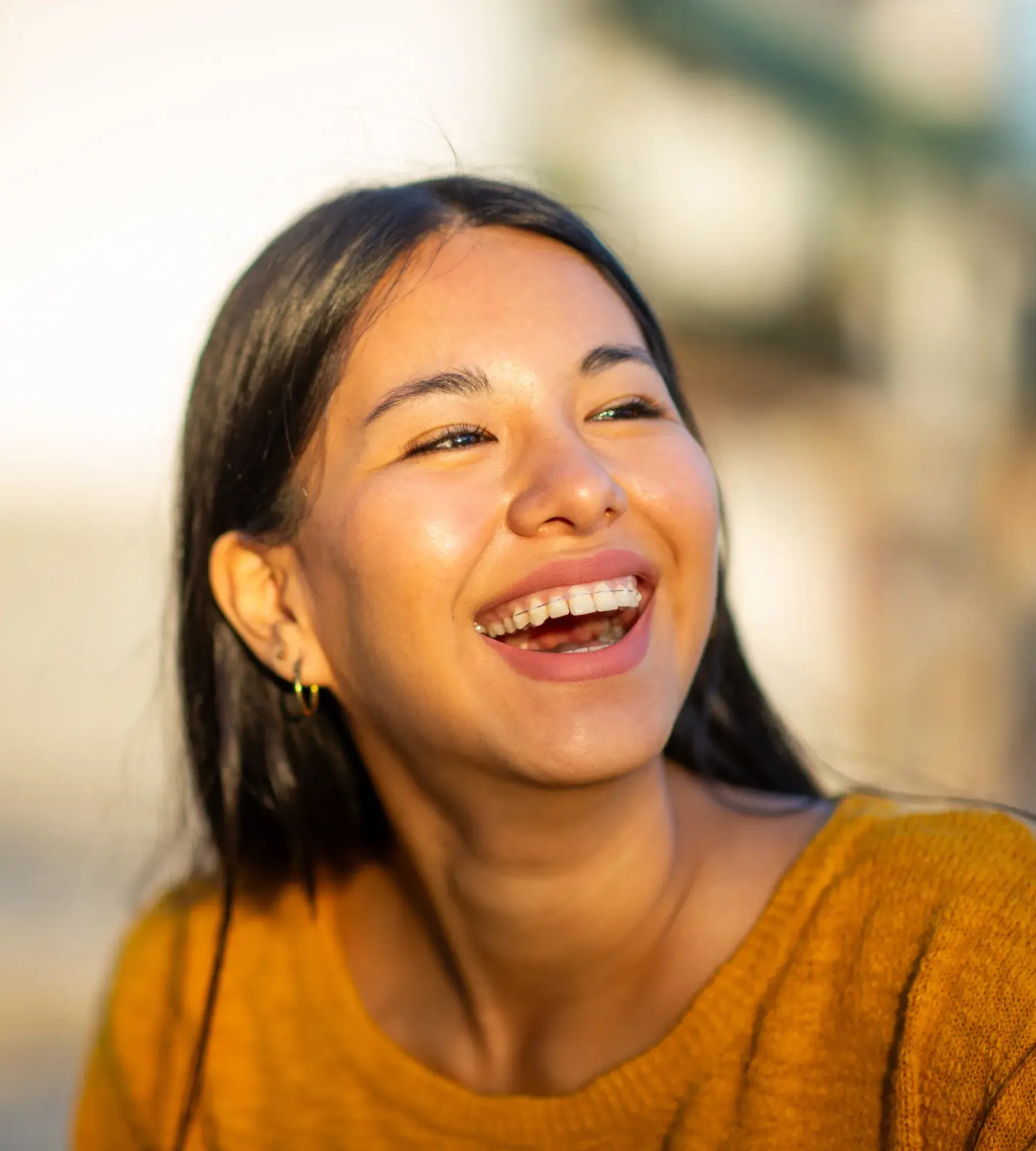 A woman in a yellow top smiles and looks to the side.