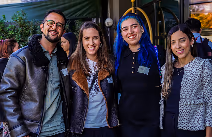Four event attendees smile for the camera in an outdoor setting, wearing name tags.