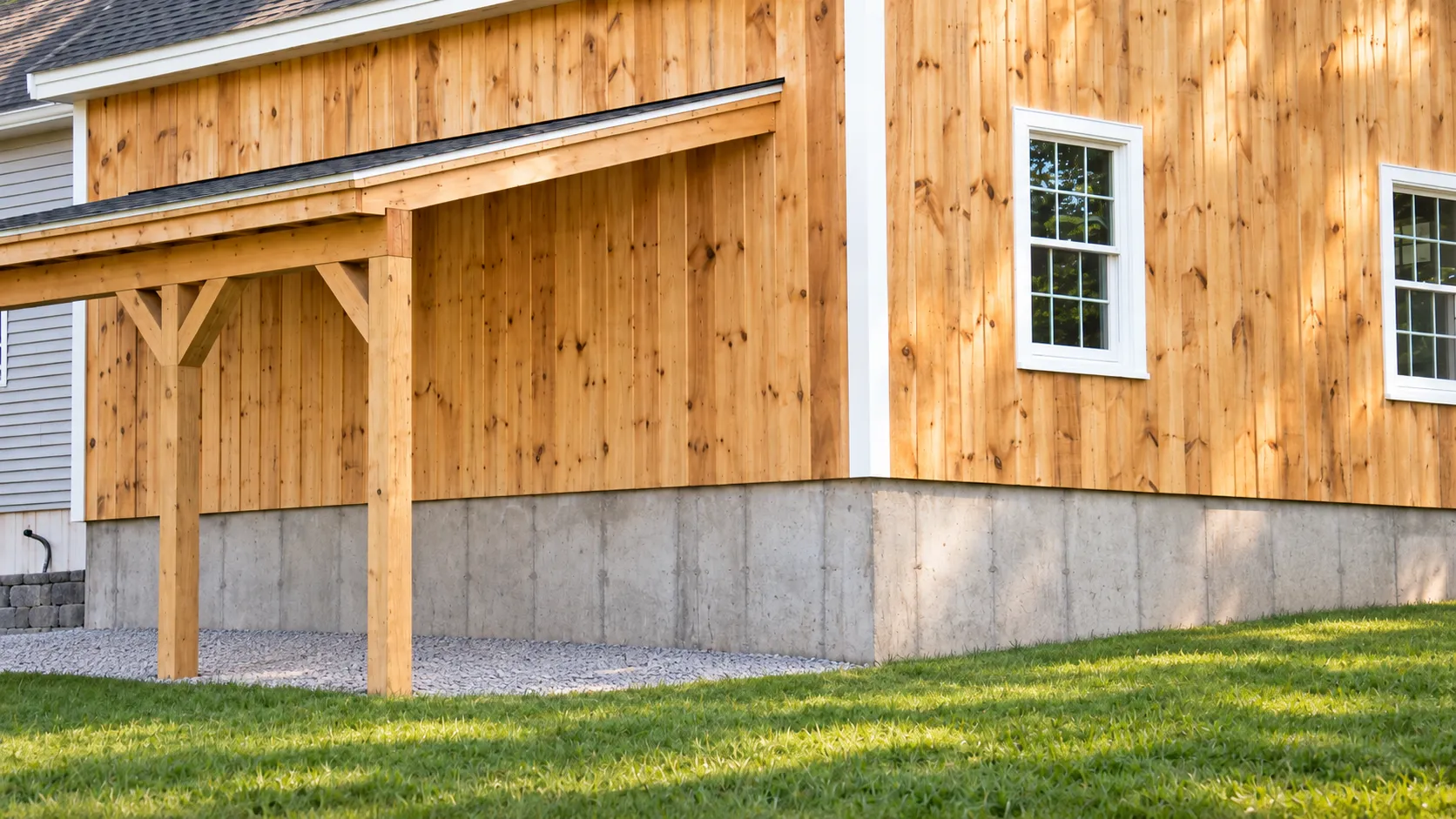 Rear corner of the Pelham, NH garage and workshop showing the lean-to posts, natural wood siding and poured foundation
