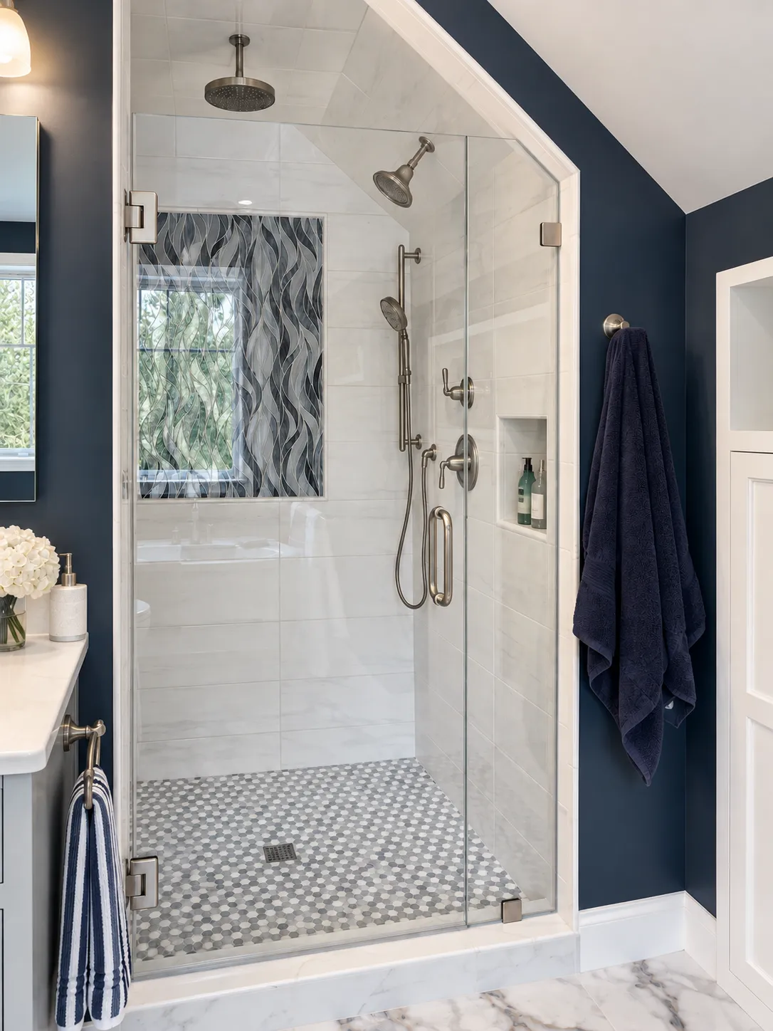 Enlarged walk-in shower in Bedford, NH with a rain head, handheld shower, blue glass wave tile accent and a hex mosaic floor