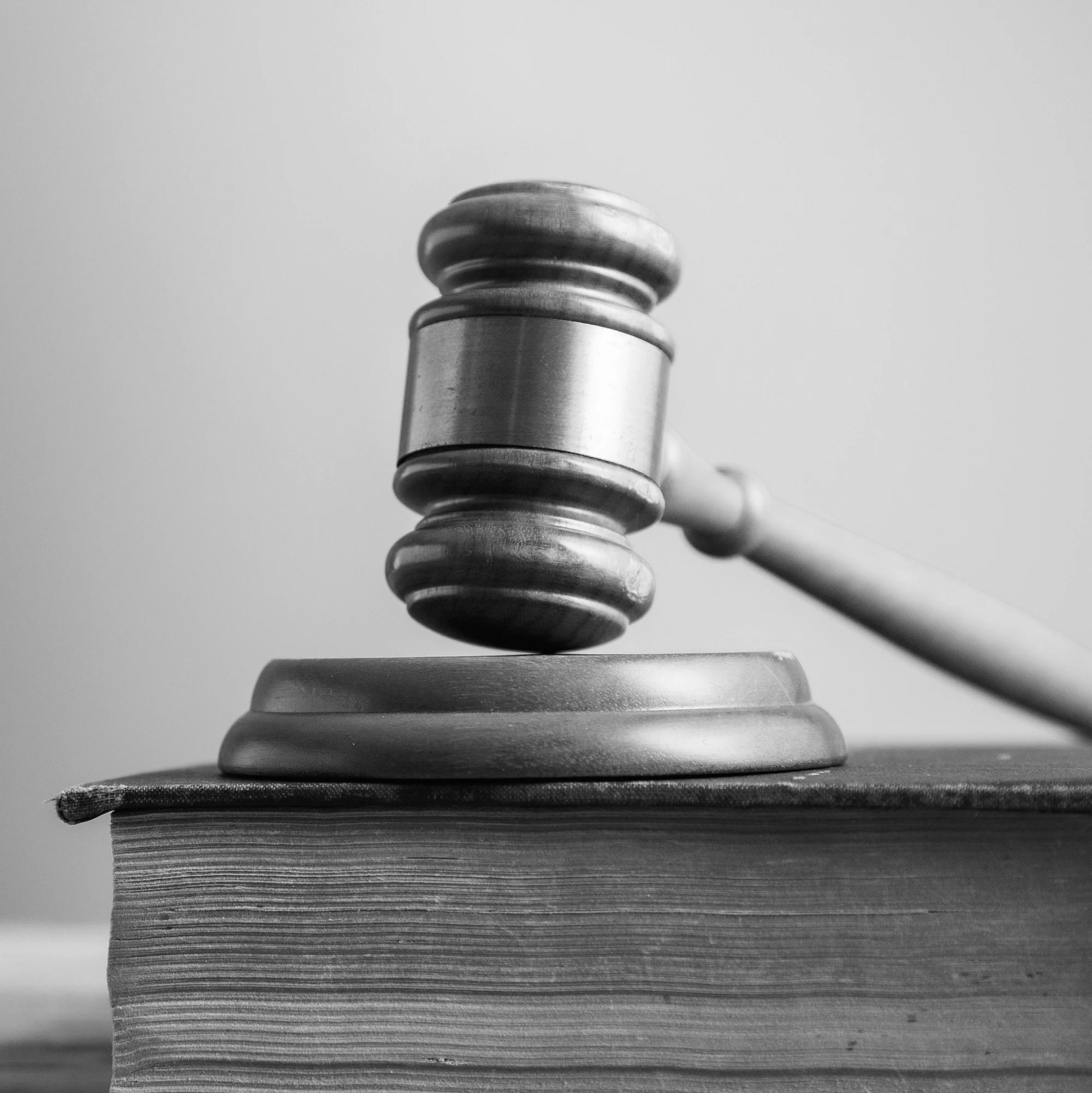 Wooden judge gavel resting on thick law book