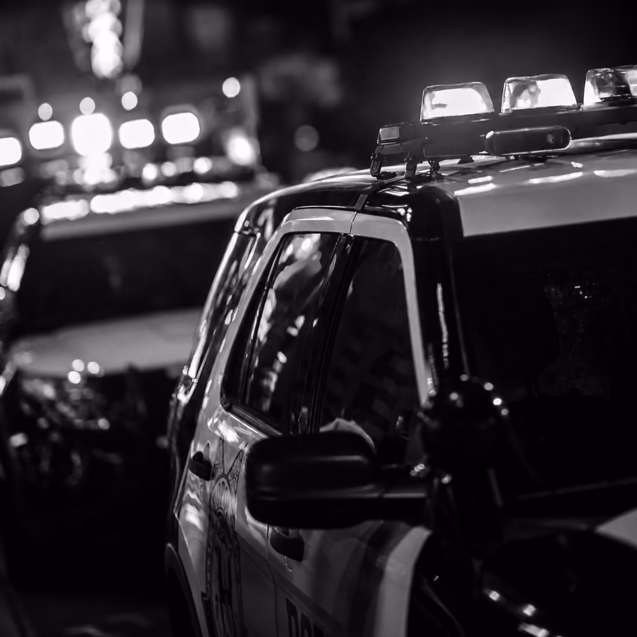 A black-and-white photo of two police cars at night