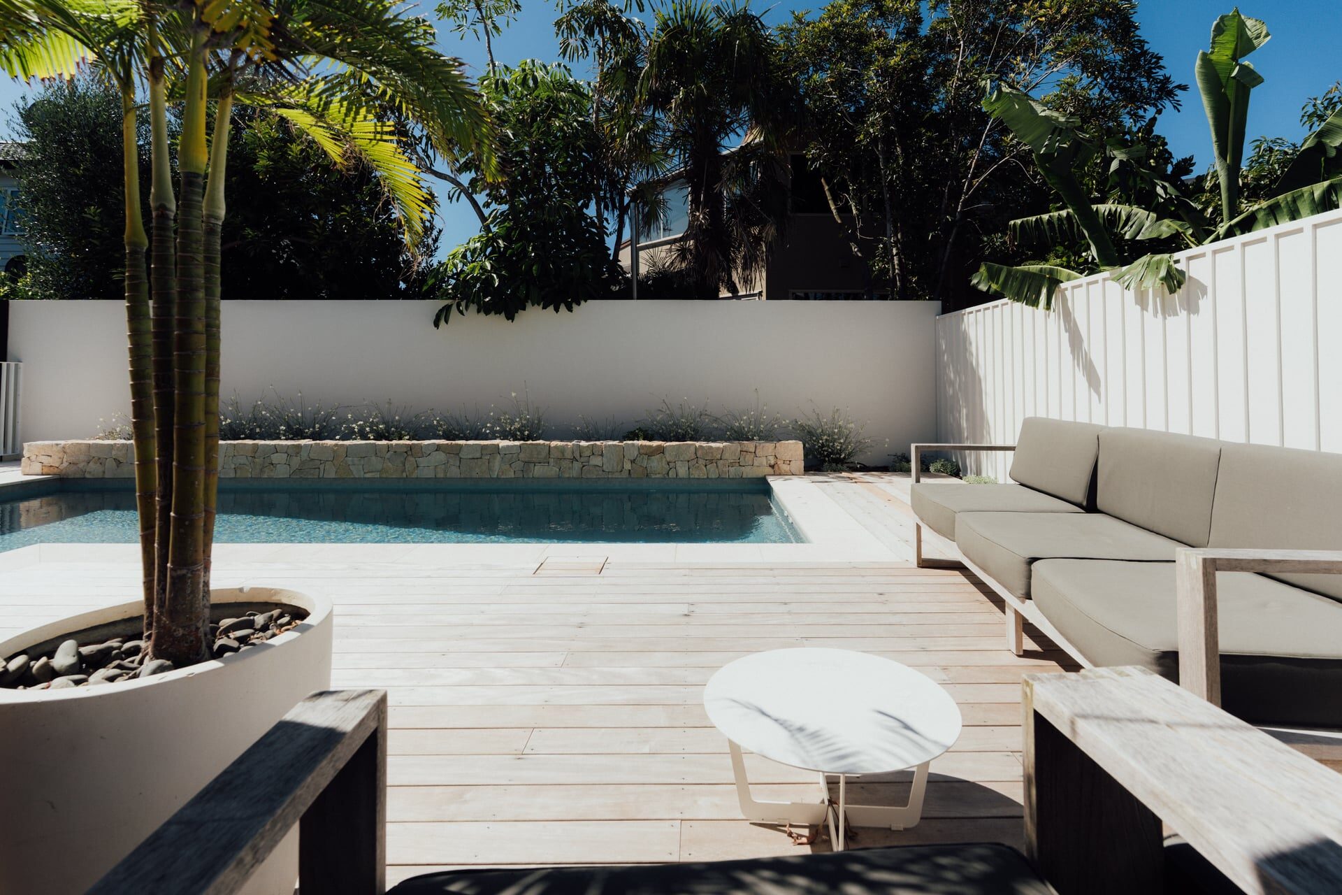 Timber deck steps leading to covered outdoor area with glass doors and ornamental grasses at Marine Parade project