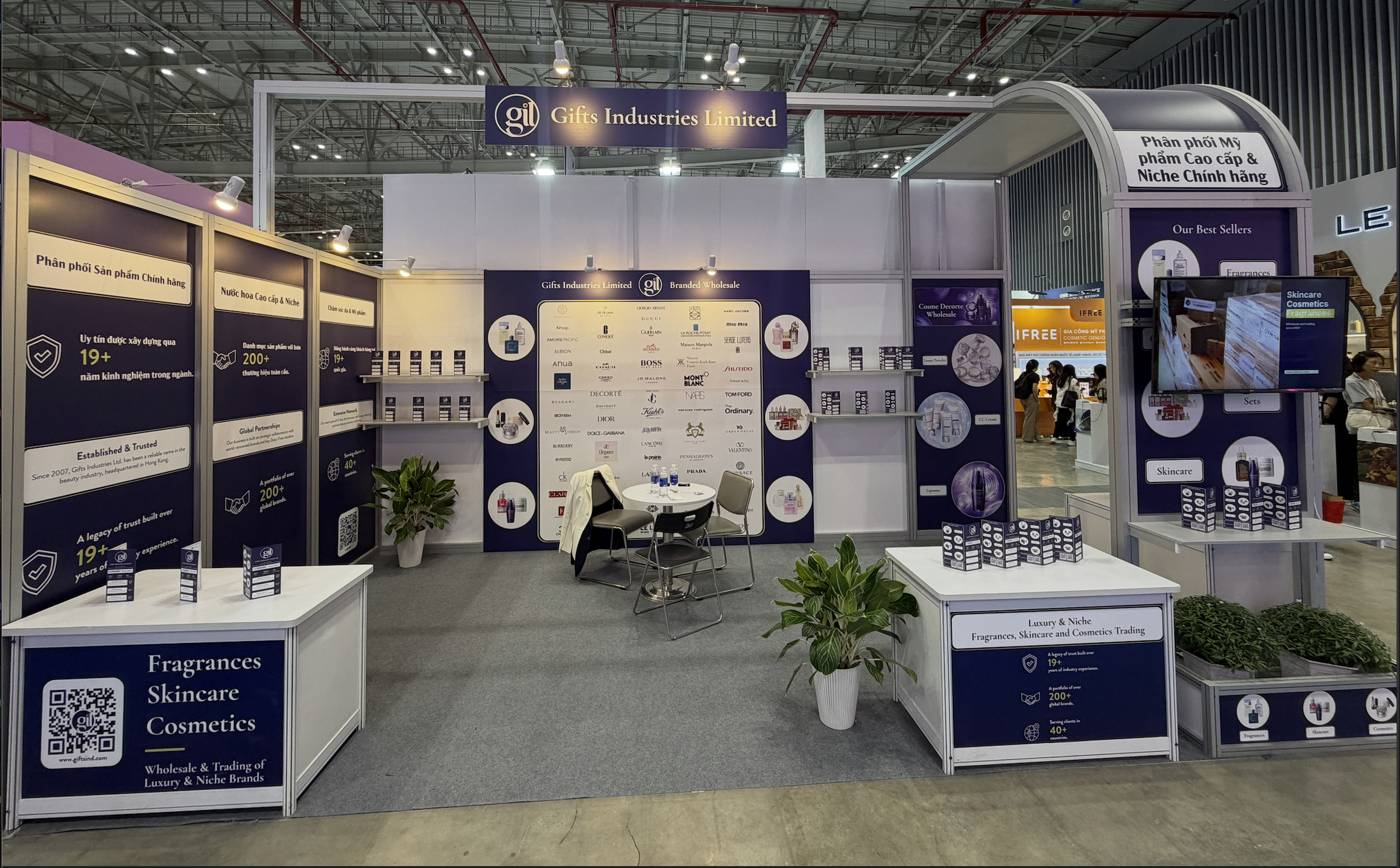 Trade show booth for Gifts Industries Limited featuring fragrance and skincare brand displays and seating area.