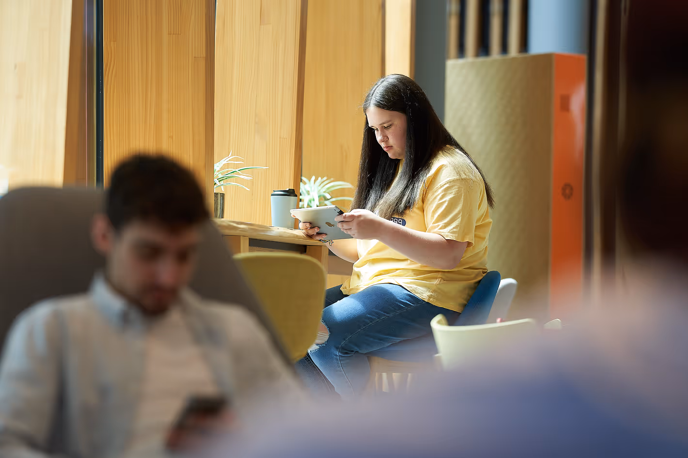 Photo of a young girl sitting indoors at a table on a tablet