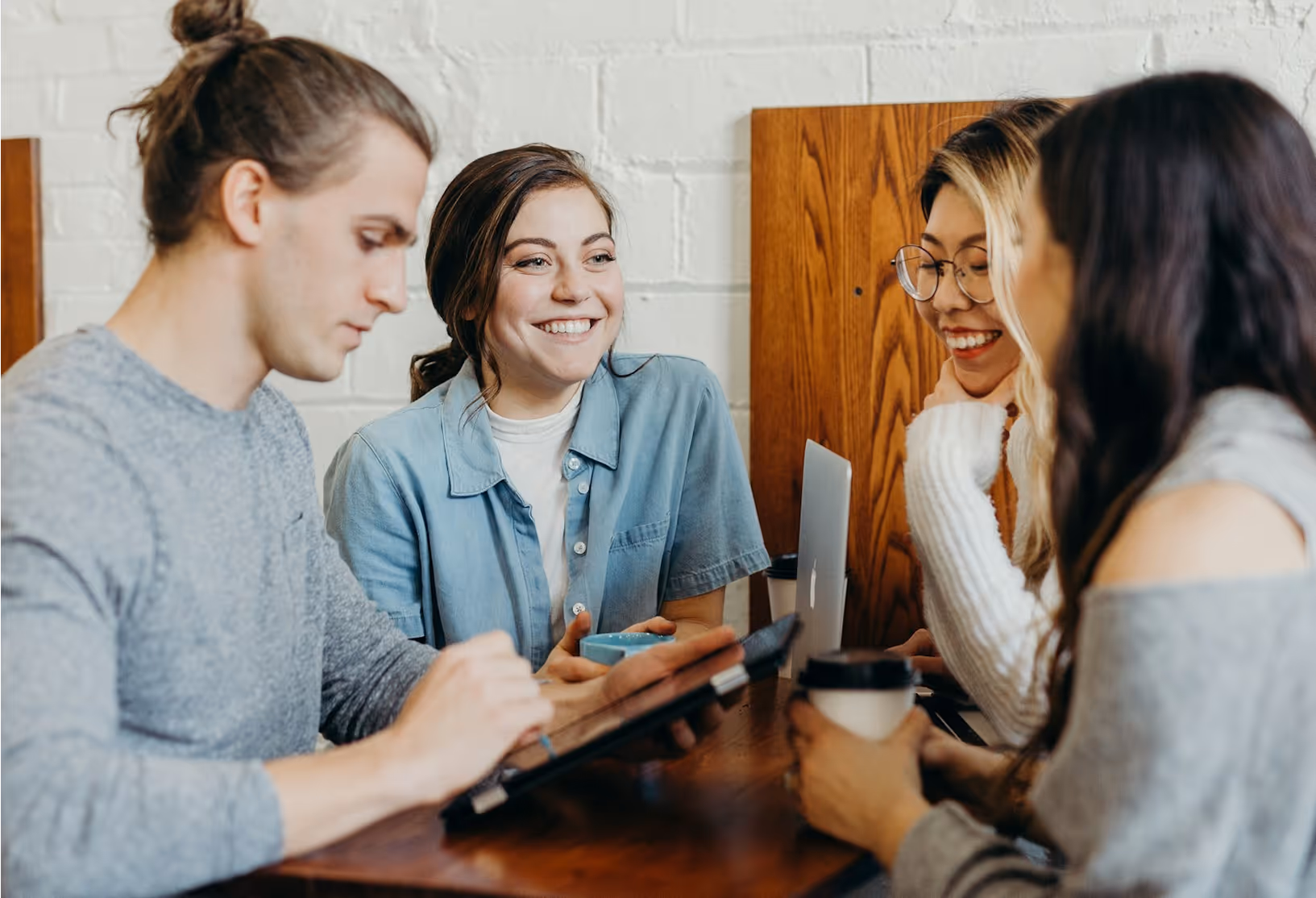 Photo of young people sitting inside around a table, laughing