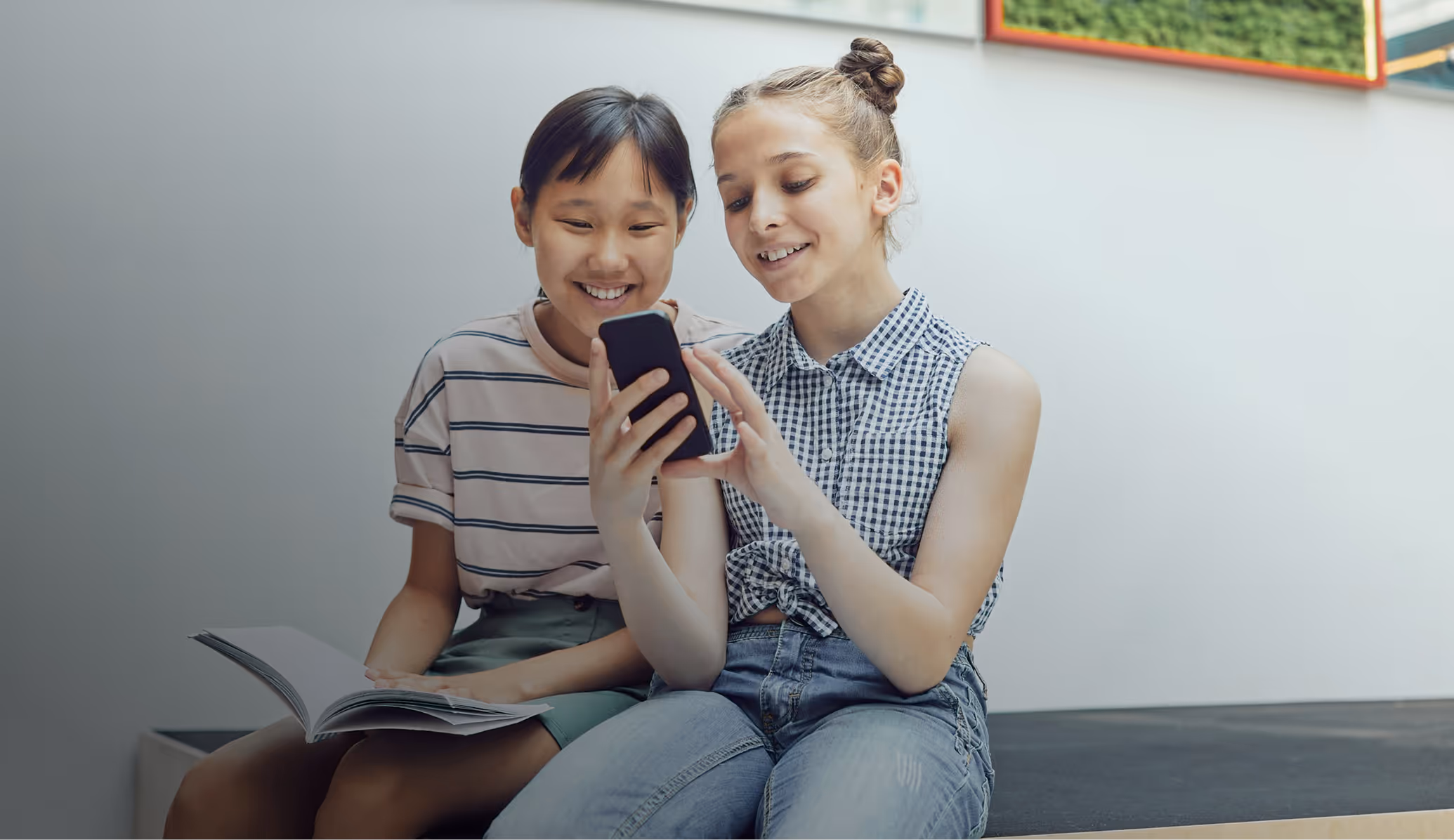 Photo of two young girls looking at an smart phone