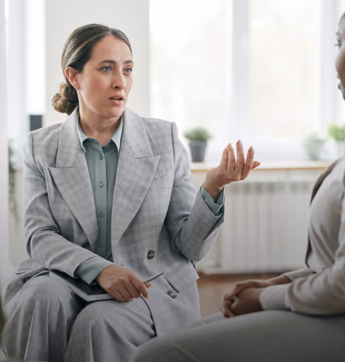 Women wearing a suit sitting on a chair chatting to a young person