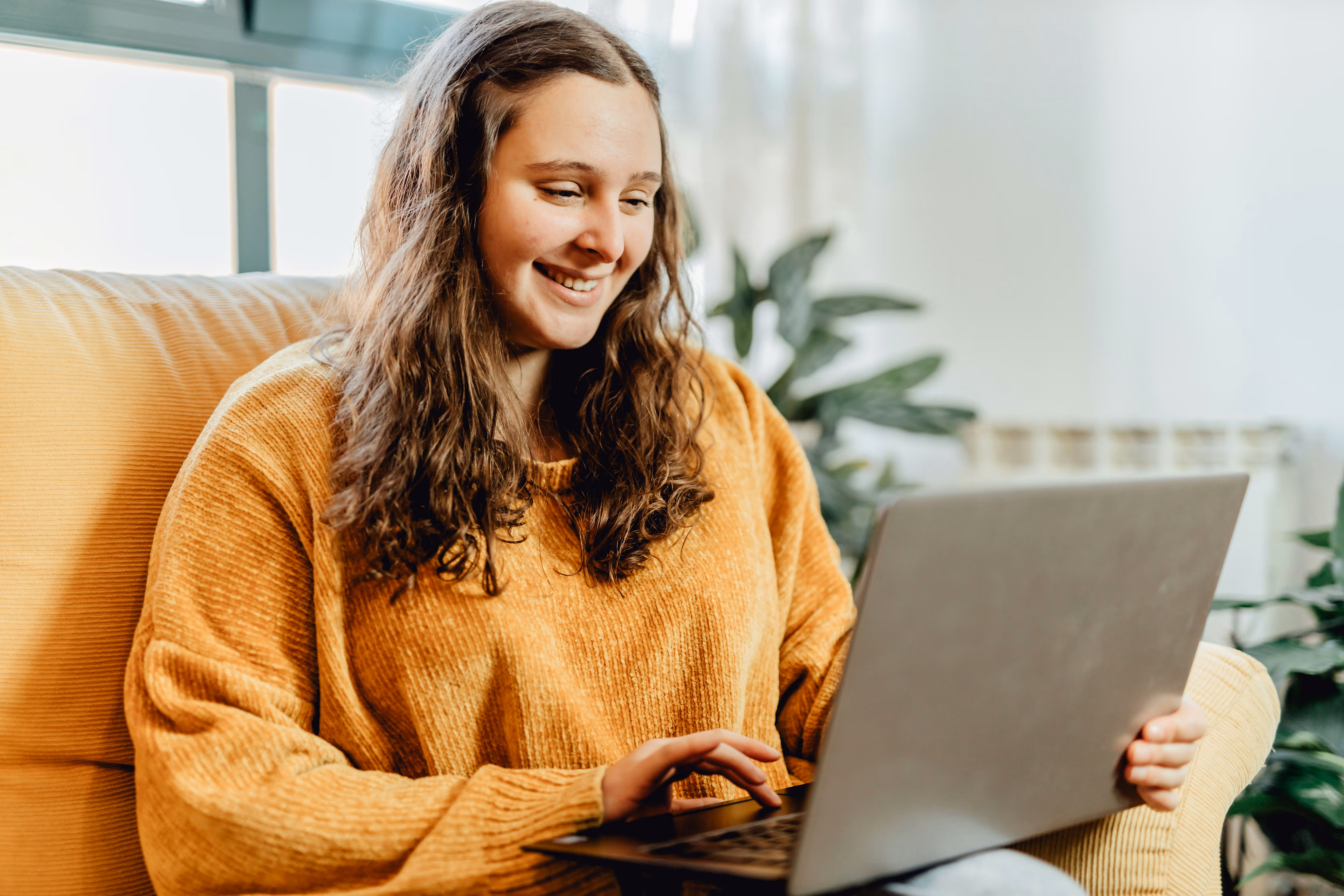 Photo of young girl on lap top on couch, smiling