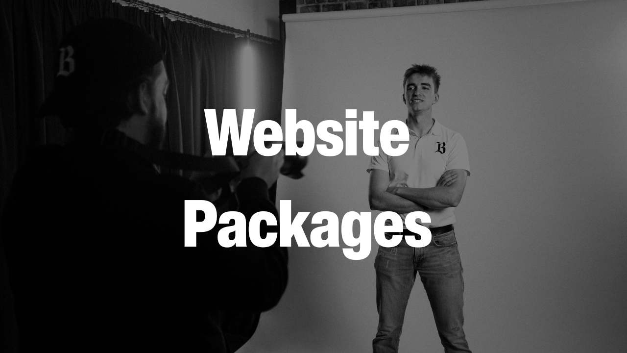 Black and white photo of a photographer taking a picture of a young man standing with arms crossed in front of a backdrop, with the text 'Website Packages' overlaying the image.