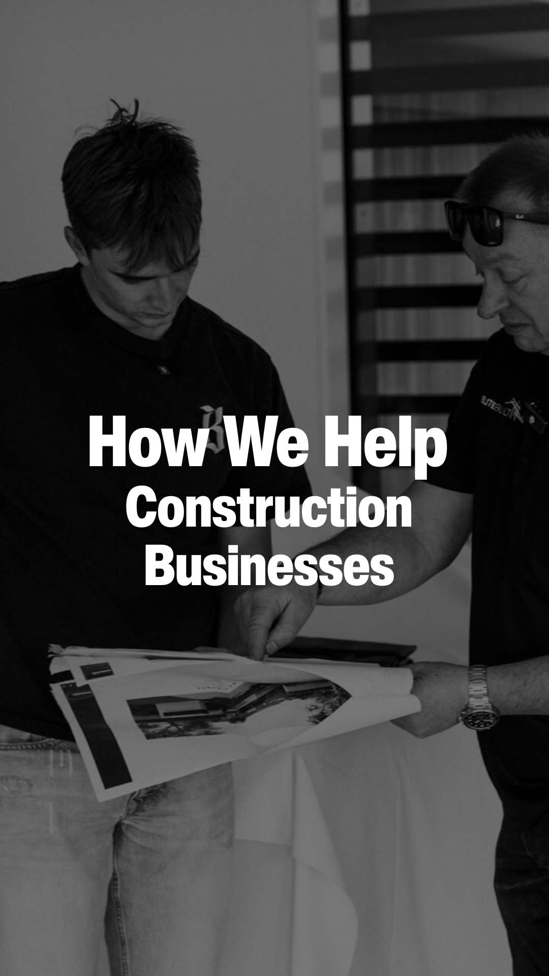 Two men reviewing construction plans or blueprints together indoors.