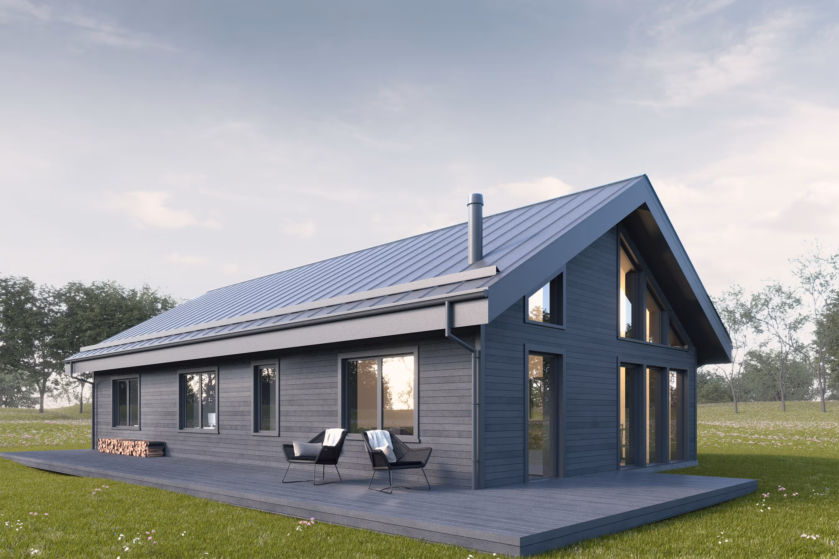 Modern dark gray wooden house with large windows, a sloped metal roof, a chimney, and a deck with two black chairs in a grassy area.