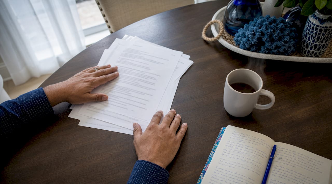 Hands sorting mortgage refinance papers on kitchen table