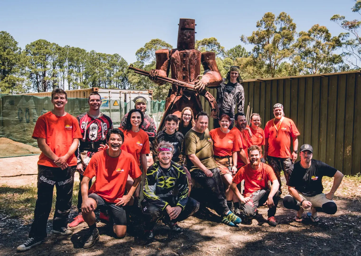 A person wearing a colorful paintball mask that features a striking design, with vibrant splashes of paint surrounding them. Dressed in a camouflage jacket, they stand confidently, ready for action at a Central Coast paintball field.