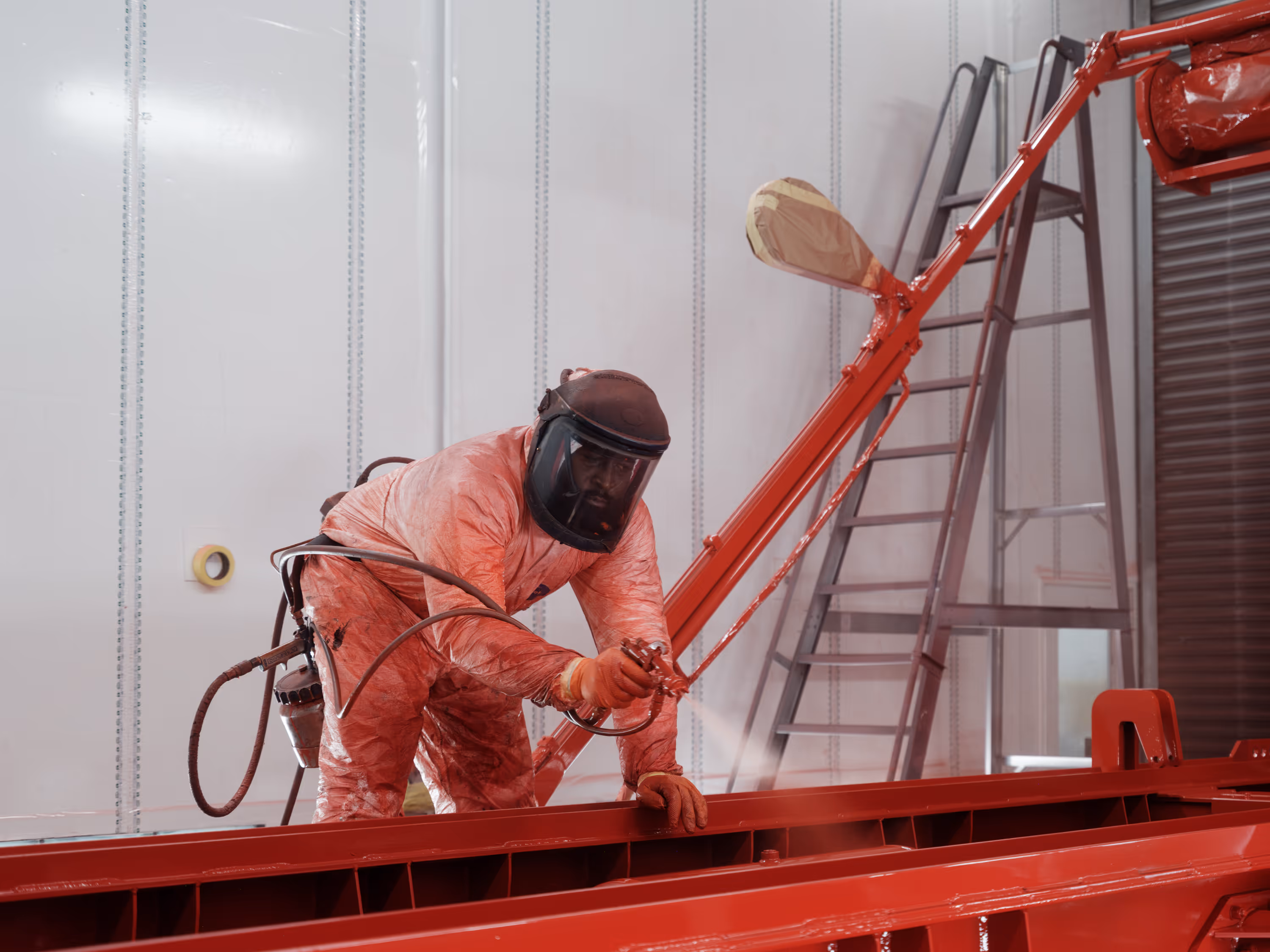 WCC staff member spraying a truck chassis red in the workshop, alternative angle.