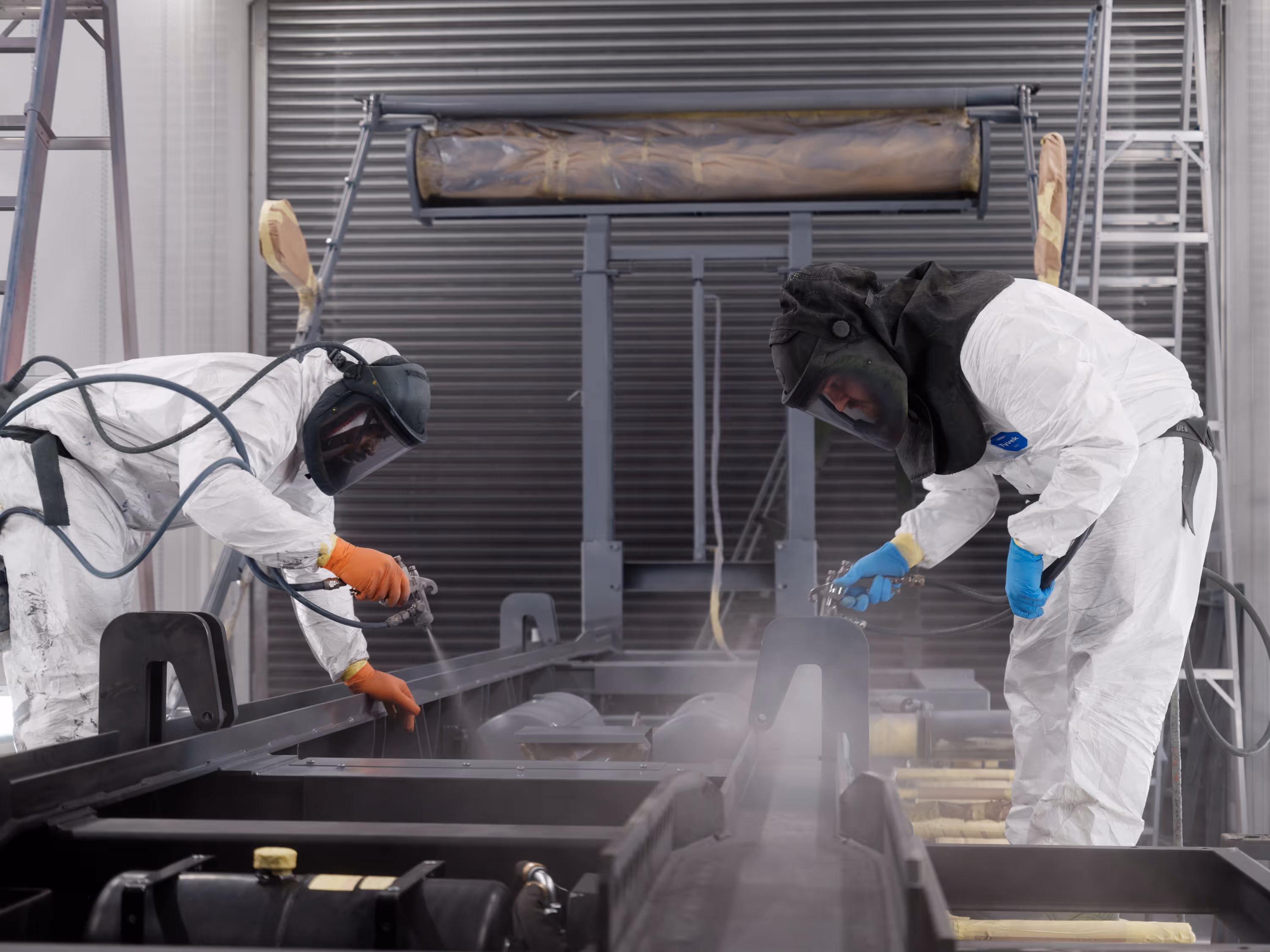 Two WCC staff members spraying primer on a truck chassis in the workshop.