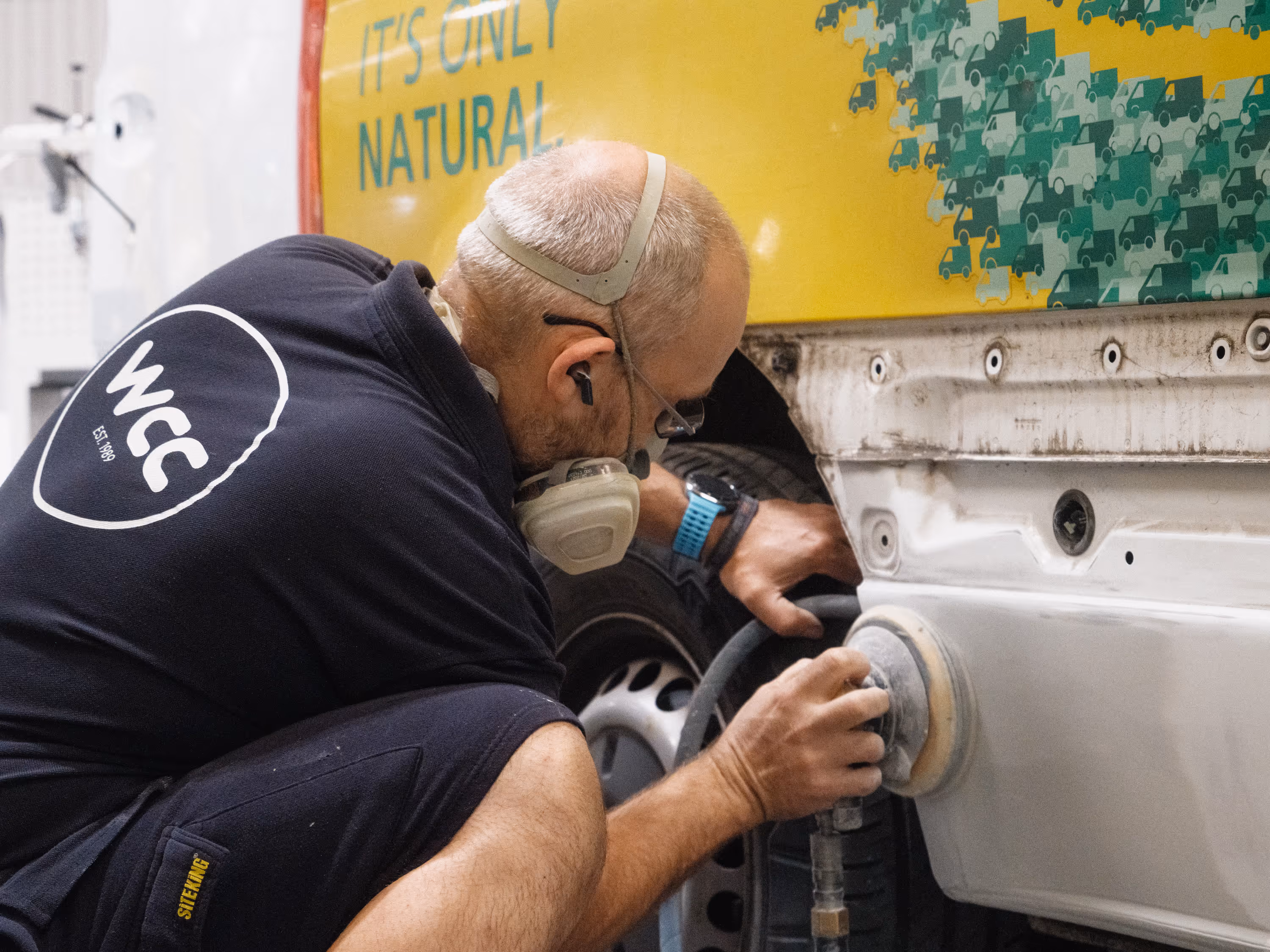 WCC staff member sanding the rear quarter panel of a DHL vehicle during accident repair.