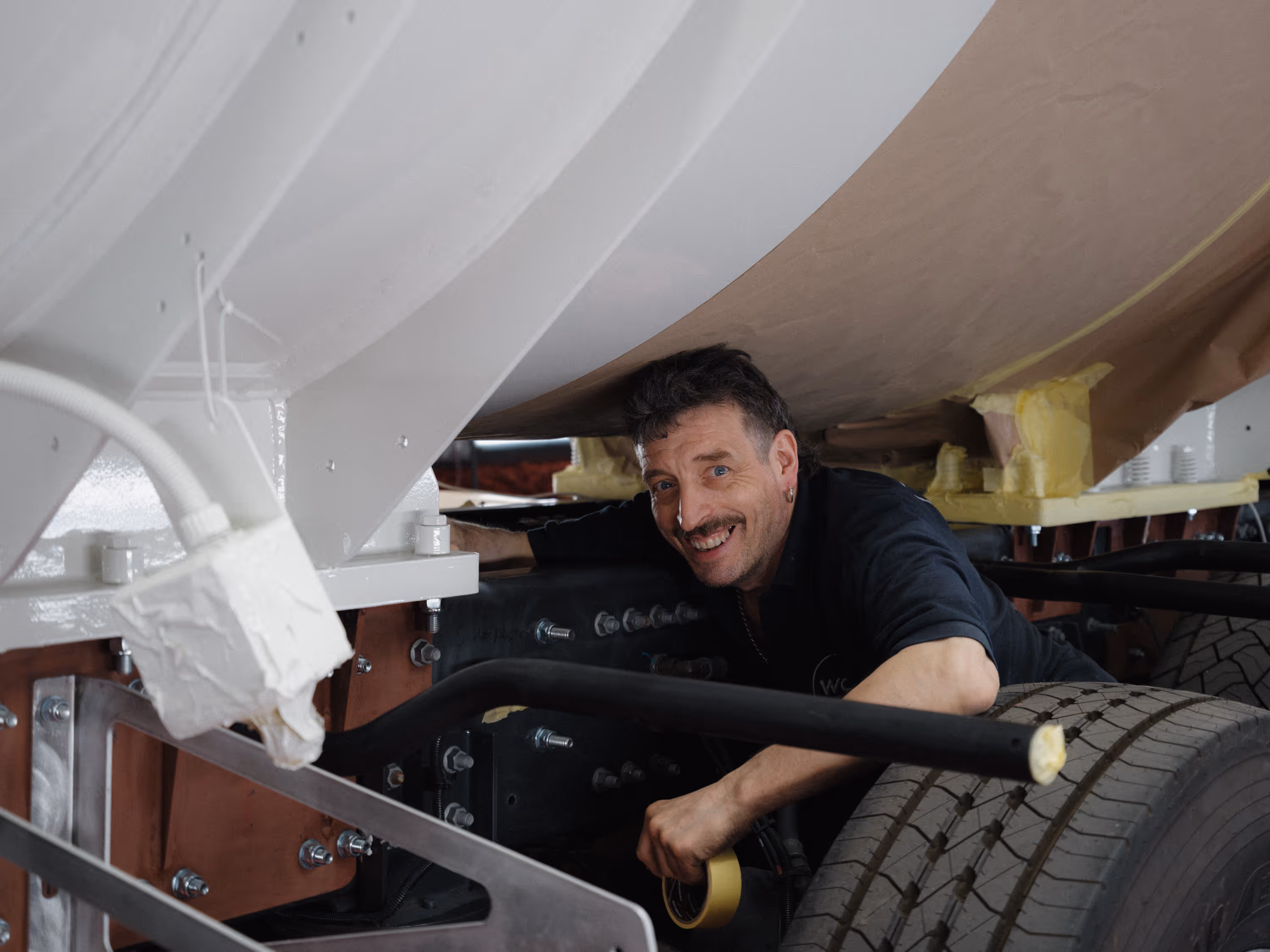 A WCC worker smiling prepping a cement mixer for paint.