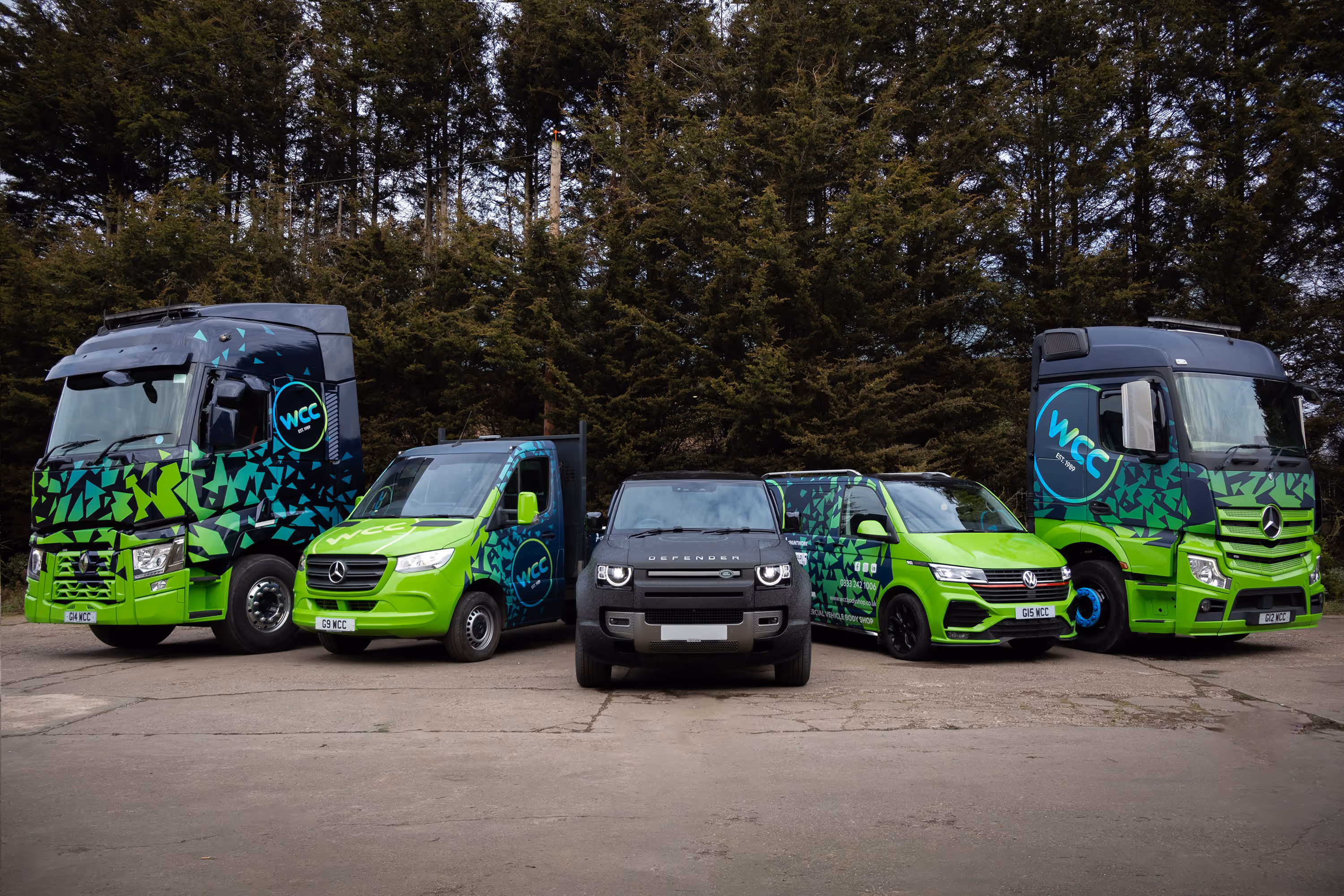 Five WCC vehicles with green and blue livery design parked in car park.