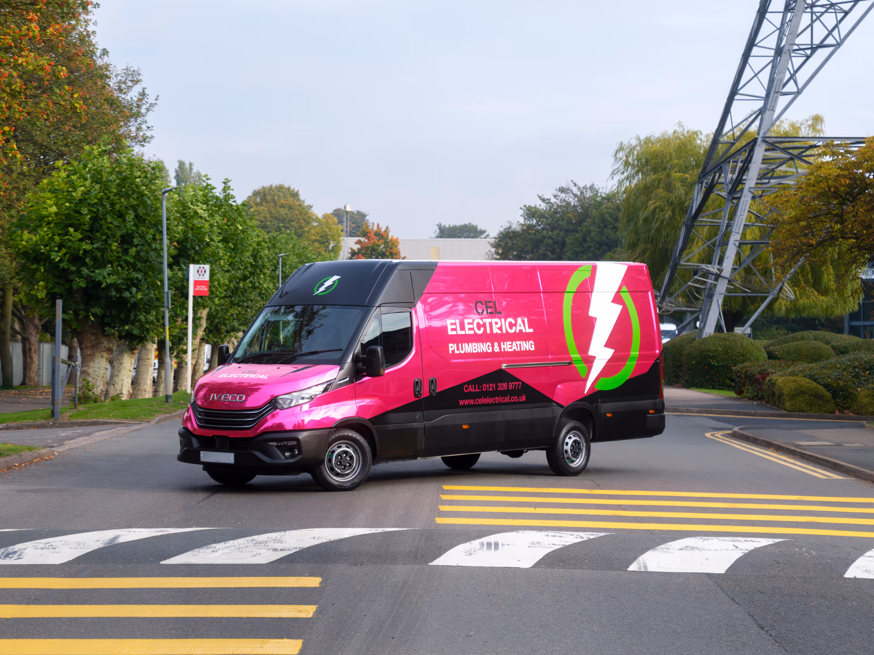 Bright pink and black electrical service van on a street crossing.