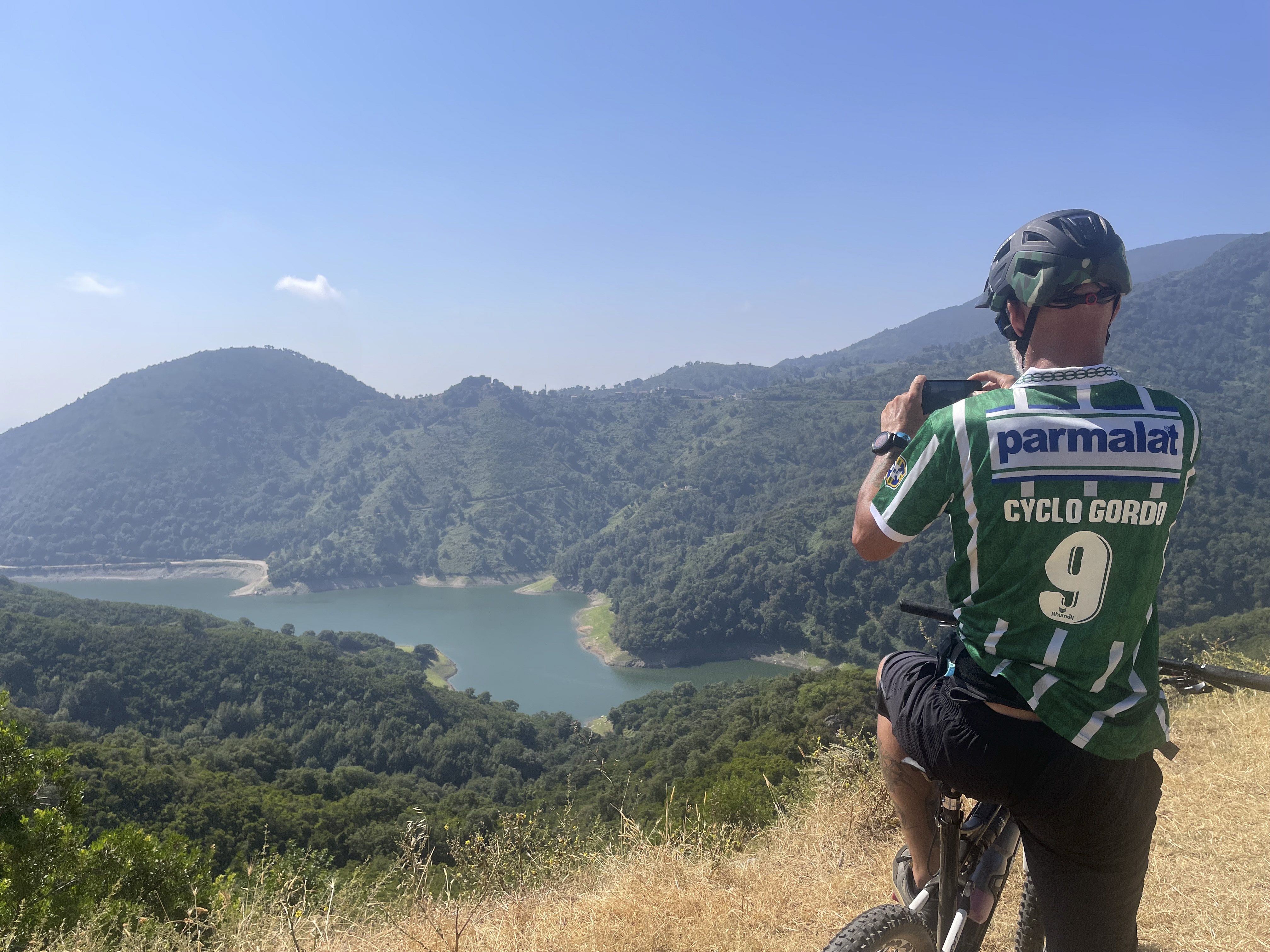 Cycliste en maillot CycloGordo face à un lac de montagne en Corse