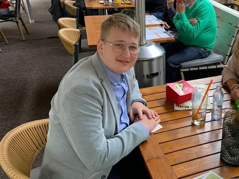 Junger Mann mit Brille im grauen Sakko beim Restaurantbesuch, frühes Bild vor Transformation