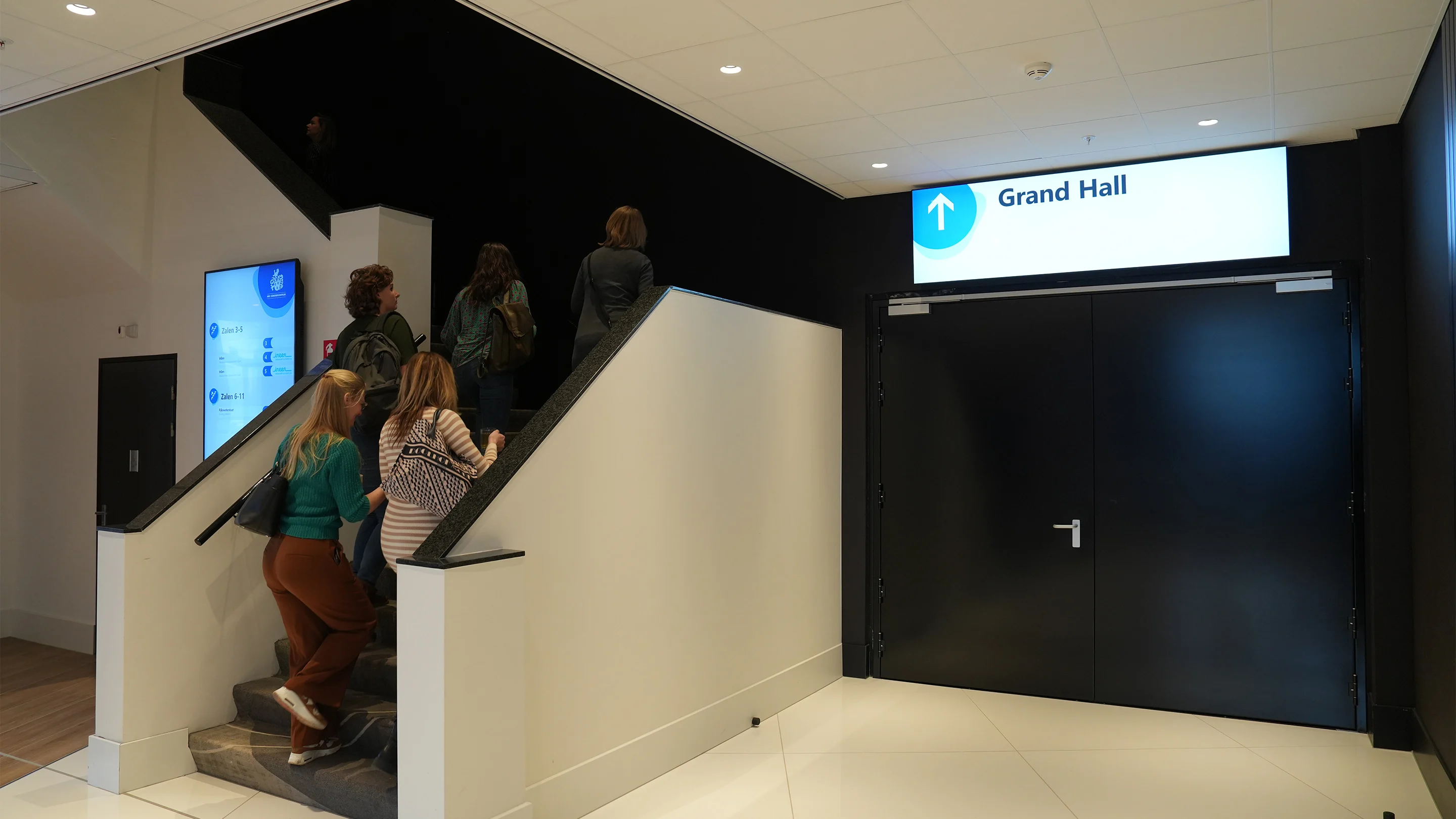 People walking up the stairs next to Merford's M-series doors at the NBC Congress Centre.