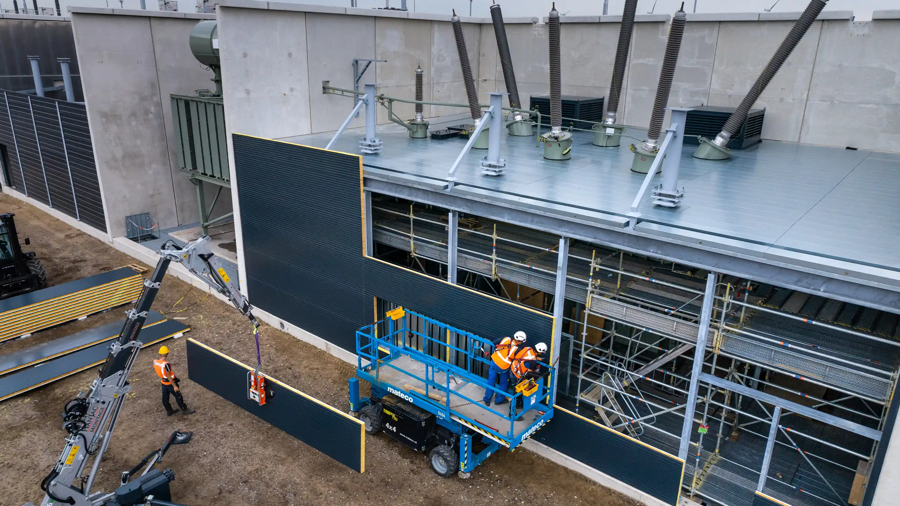 Workers installing modular sound panels around a transformer station to reduce industrial noise.