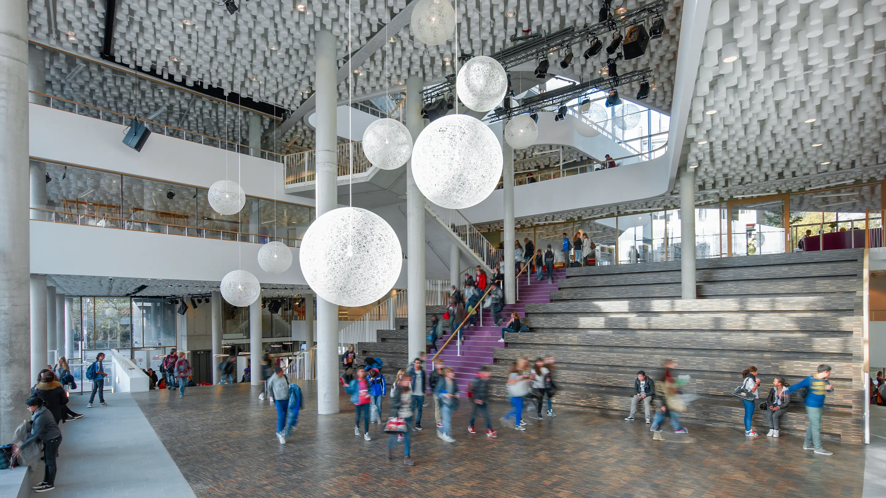 Interieur van een schoolauditorium met akoestische plafondpanelen voor verbeterde ruimteakoestiek.