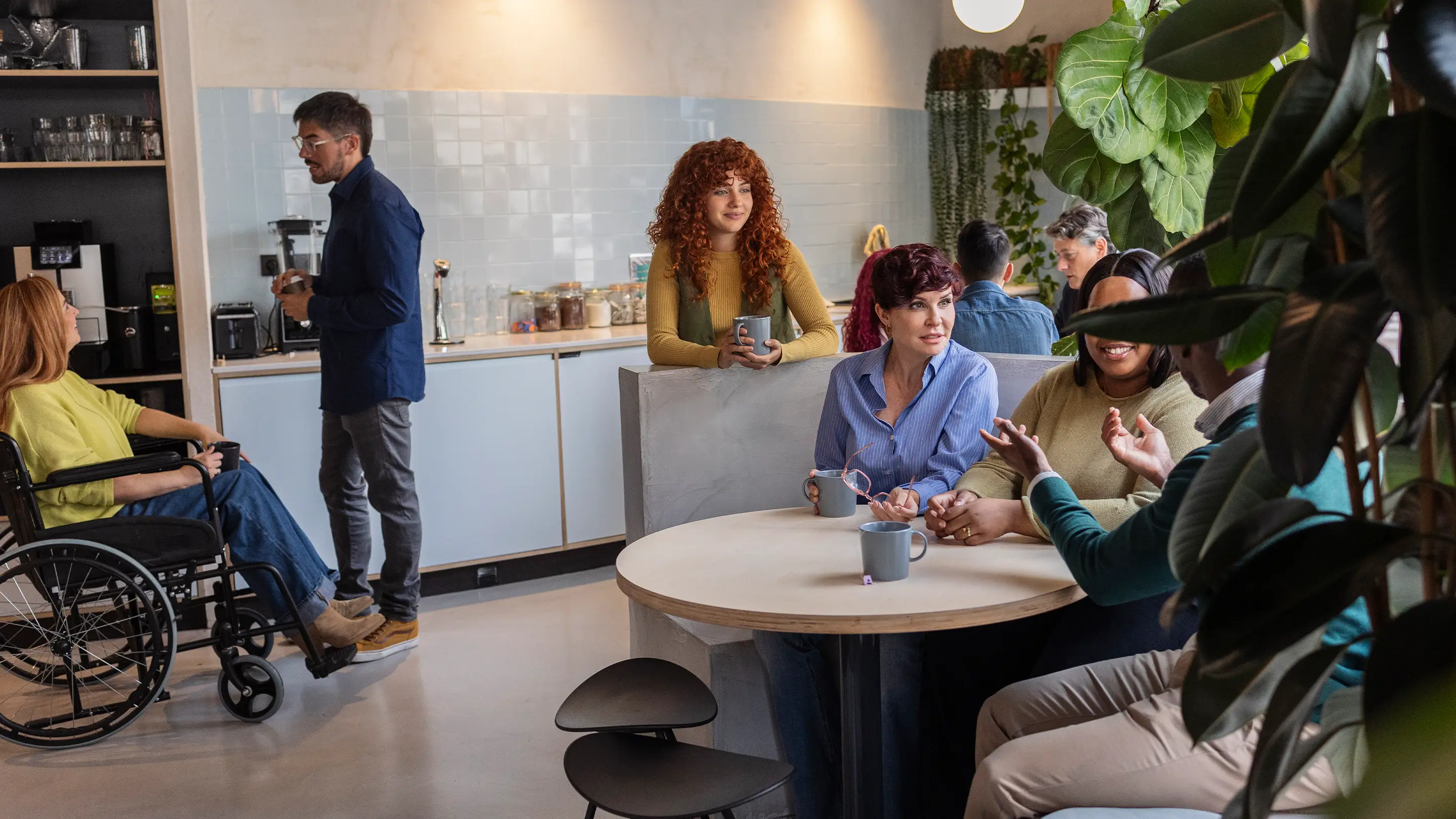Mensen die interactie hebben in een gemeenschappelijke ruimte, ontworpen met akoestische oplossingen voor comfort, concentratie en welzijn.