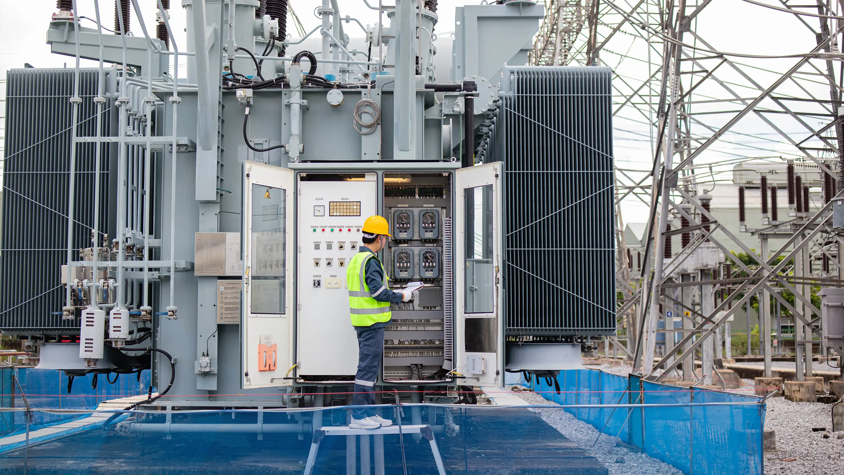 Engineer inspecting electrical transformer inside an industrial substation with acoustic enclosure.