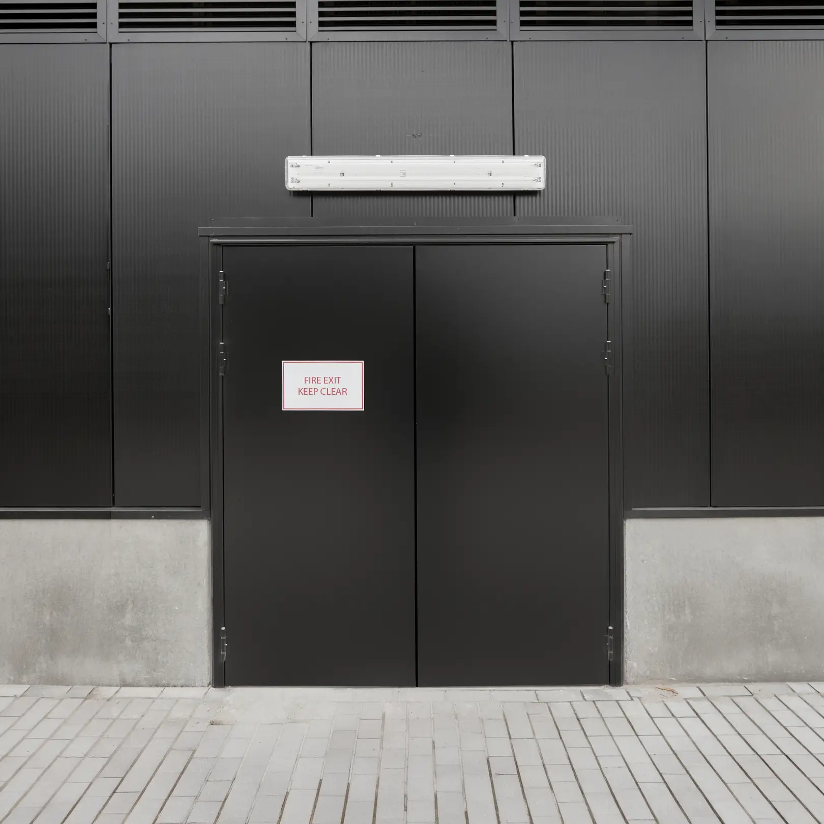 Merford steel fire exit doors installed in an industrial building façade with “Fire exit – keep clear” sign.