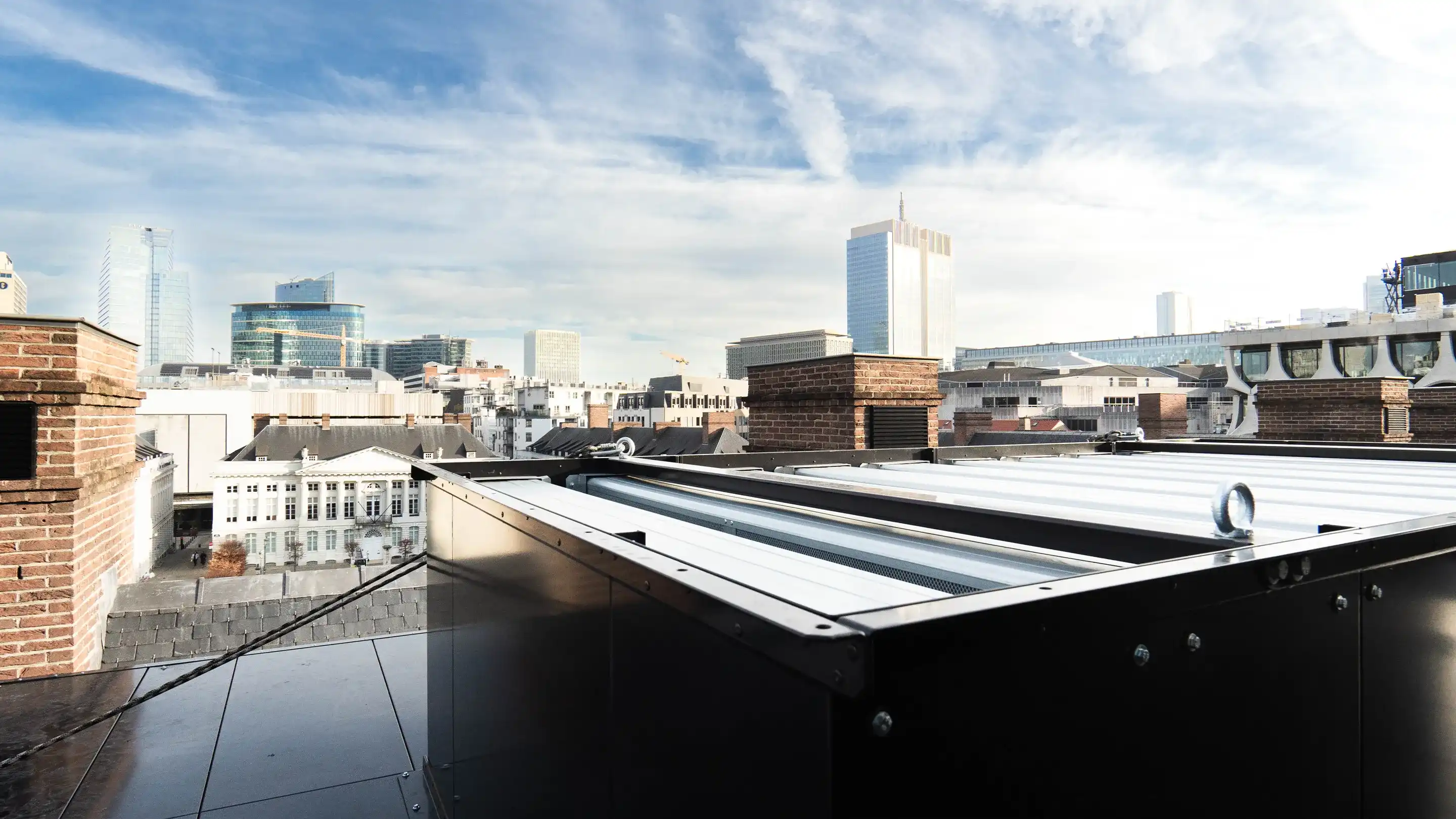 Akoestische HVAC-units op een dak met skyline van Brussel op de achtergrond.