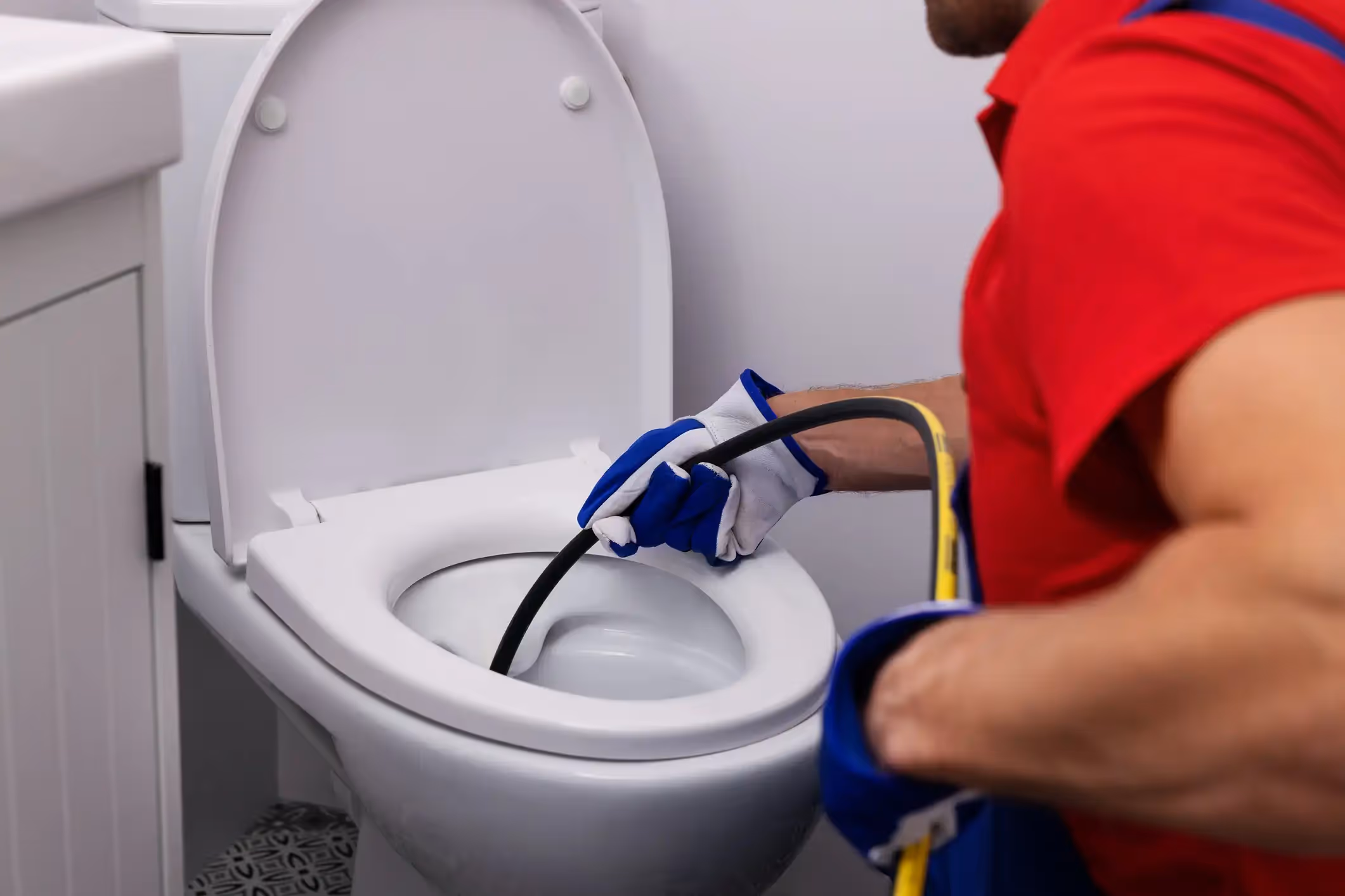 A hand in a blue rubber glove installs a new black faucet on a white sink.