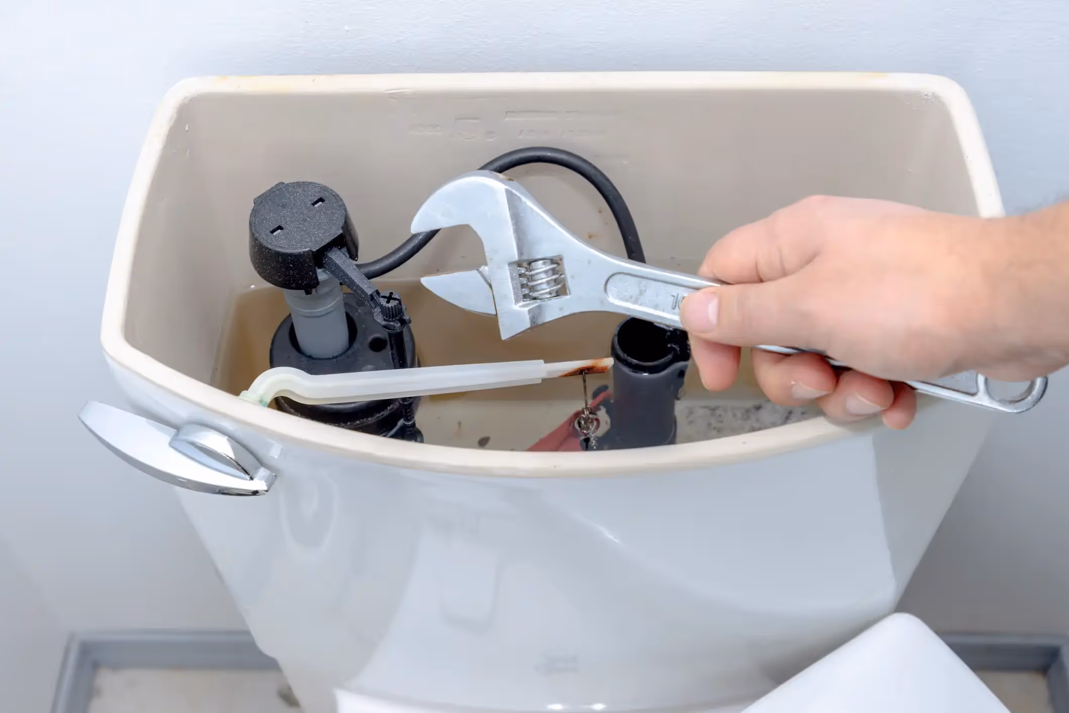 A close-up of a plumber's hands wearing blue gloves, using a wrench to work on a pipe.