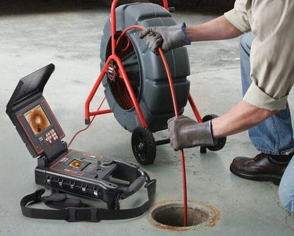 Plumber feeds camera into drain.