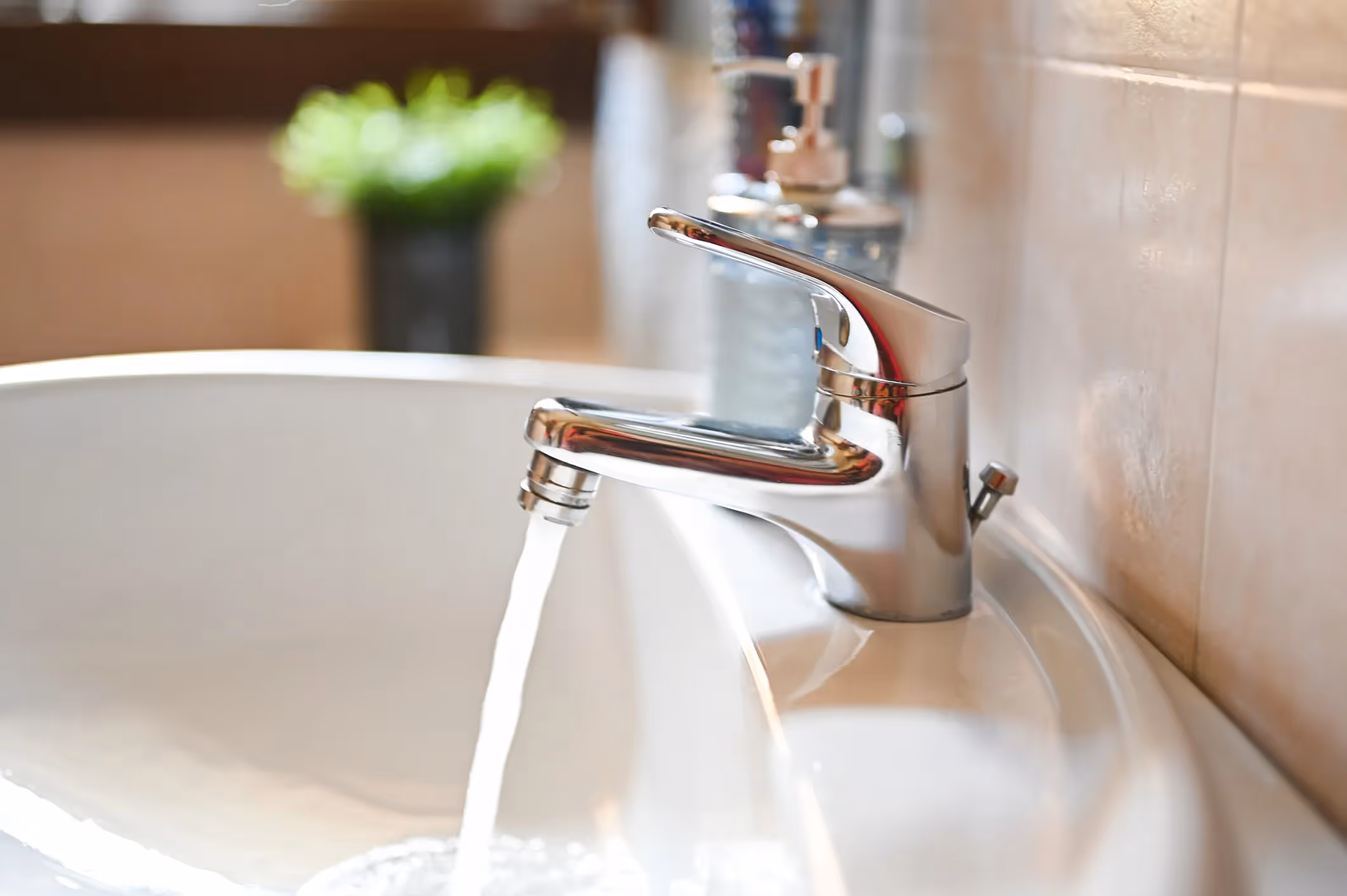 An empty white bathroom sink with a dark drain plug and a second overflow hole, set in a brown granite countertop.
