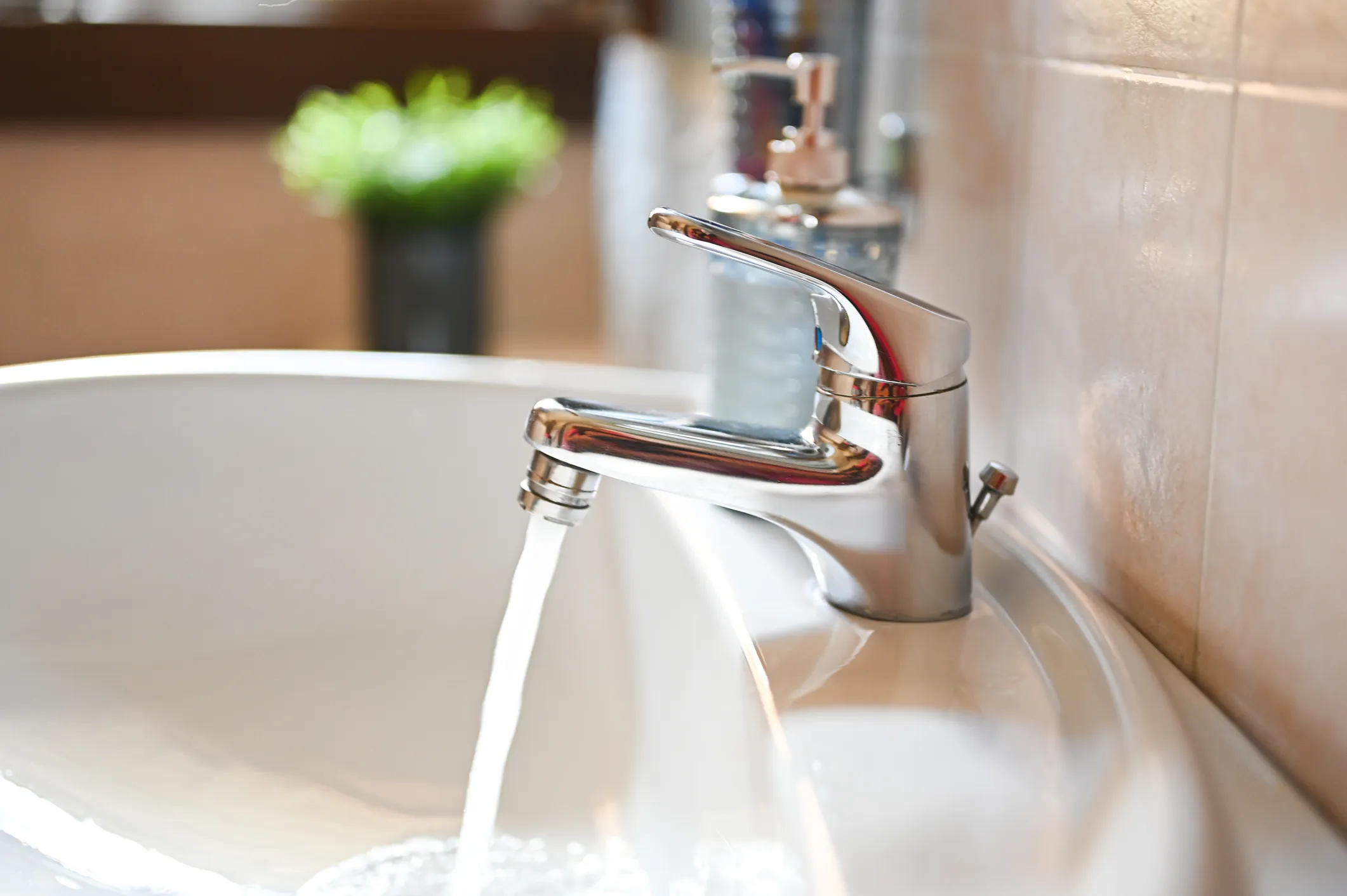 An empty white bathroom sink with a dark drain plug and a second overflow hole, set in a brown granite countertop.