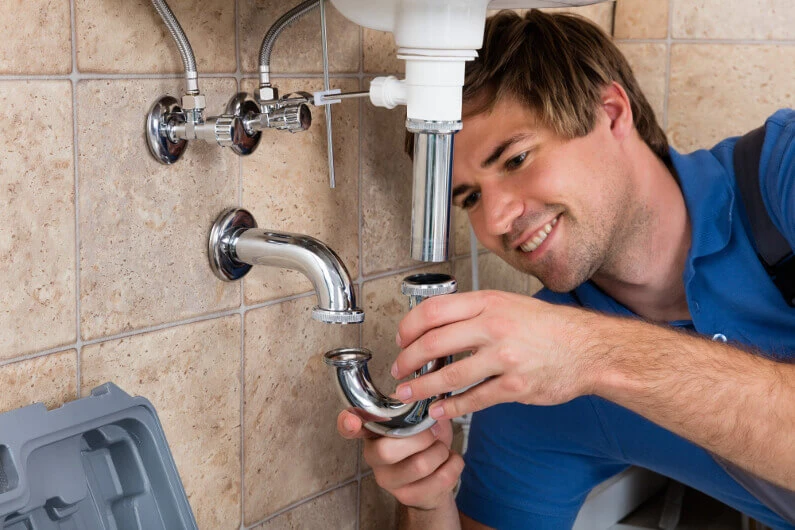 Happy plumber working under a sink.