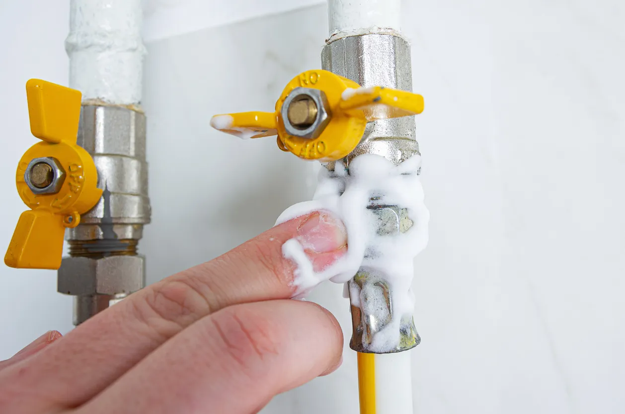A close shot of a person repairing a leaked gas line pipe