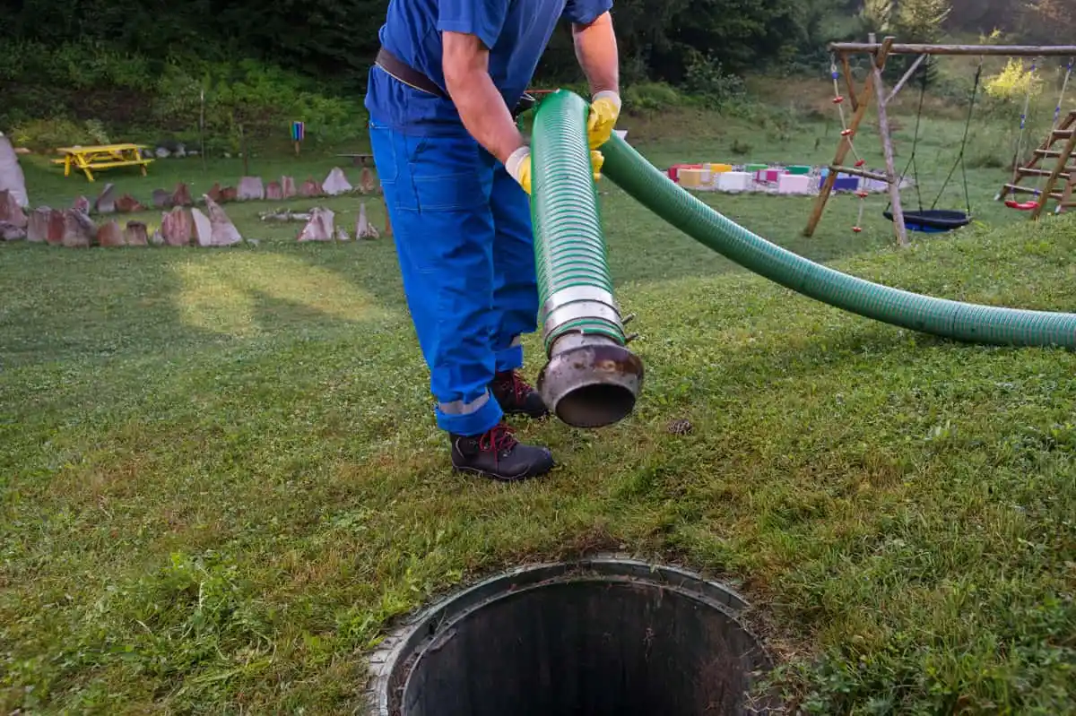 Man lowering hose into septic tank.