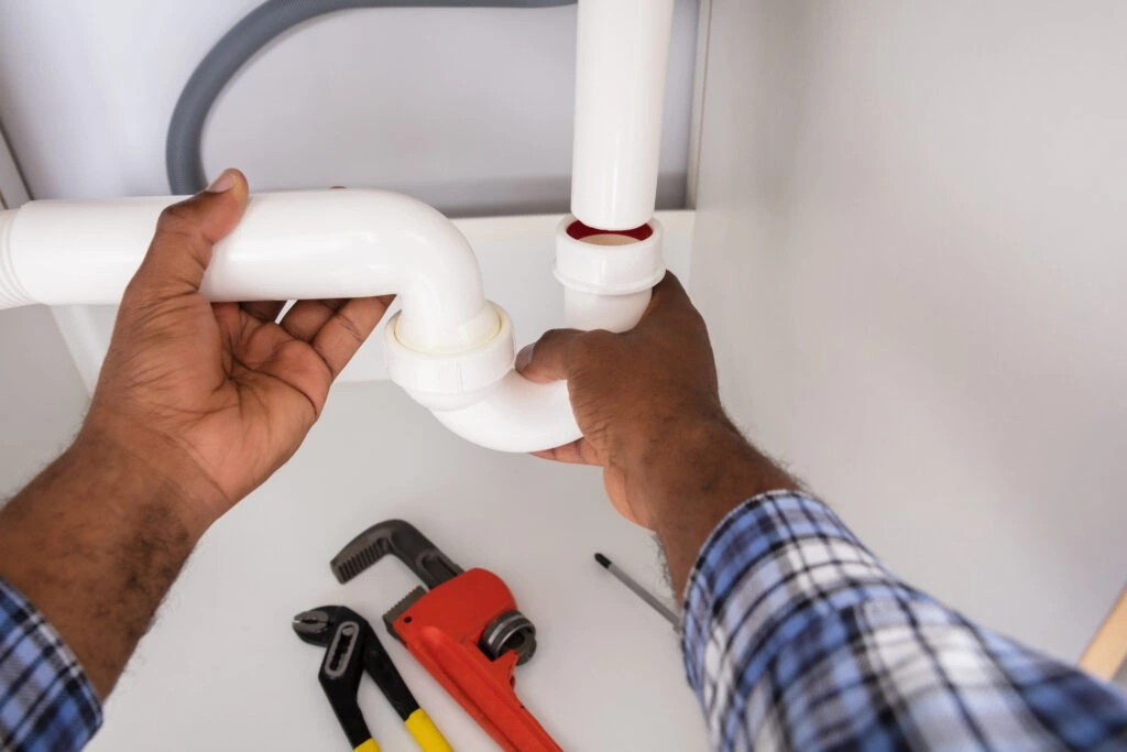 Plumber's hands working on pipes.