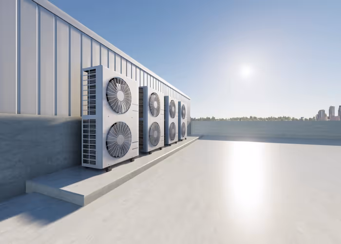 Air conditioning units line a rooftop under a clear blue sky. The sun shines brightly, casting reflections on the smooth surface, suggesting a warm, serene day.