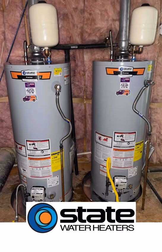 Two State Water Heaters with attached tanks standing side by side in a basement. The background is insulated with pink fiberglass. Overall industrial tone.