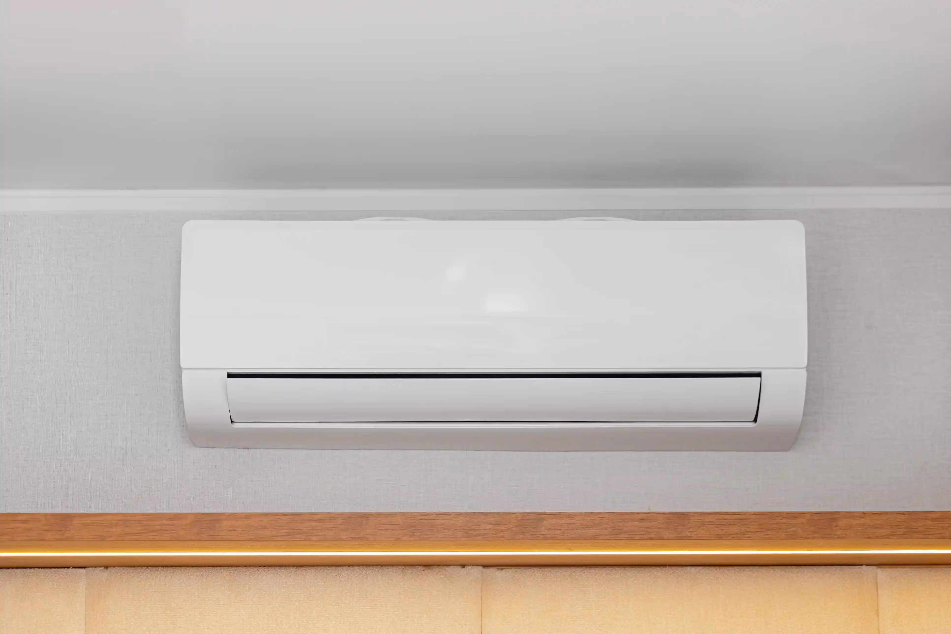 A clean, sleek white ductless air conditioner is mounted on a light-colored wall.