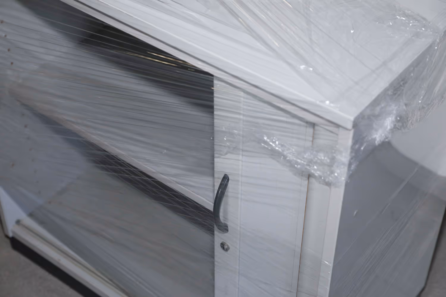 Ein leerer Aktenschrank mit Einlegeböden ist vollständig mit Schutzfolie umwickelt und für den Transport vorbereitet.