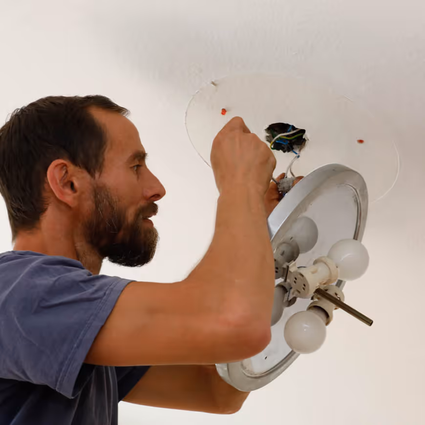 Ein Mitarbeiter von GRAVITAS demontiert eine Deckenlampe bei der professionellen Renovierungsvorbereitungen.