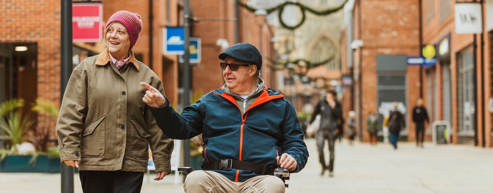 Two people on a shopping street one in a wheelchair