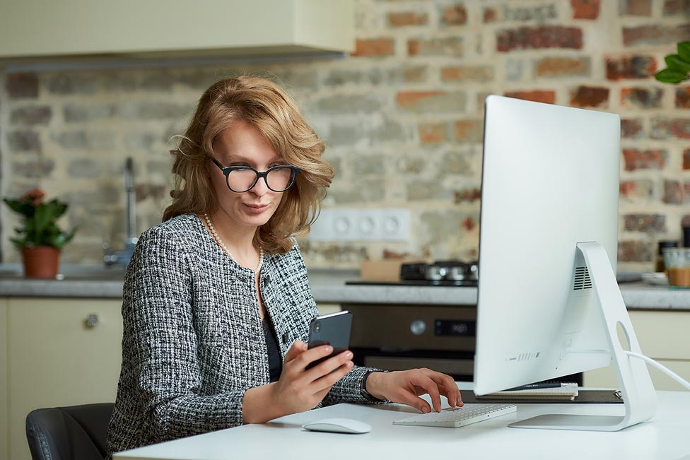 A distracted woman on her phone during an online meeting.